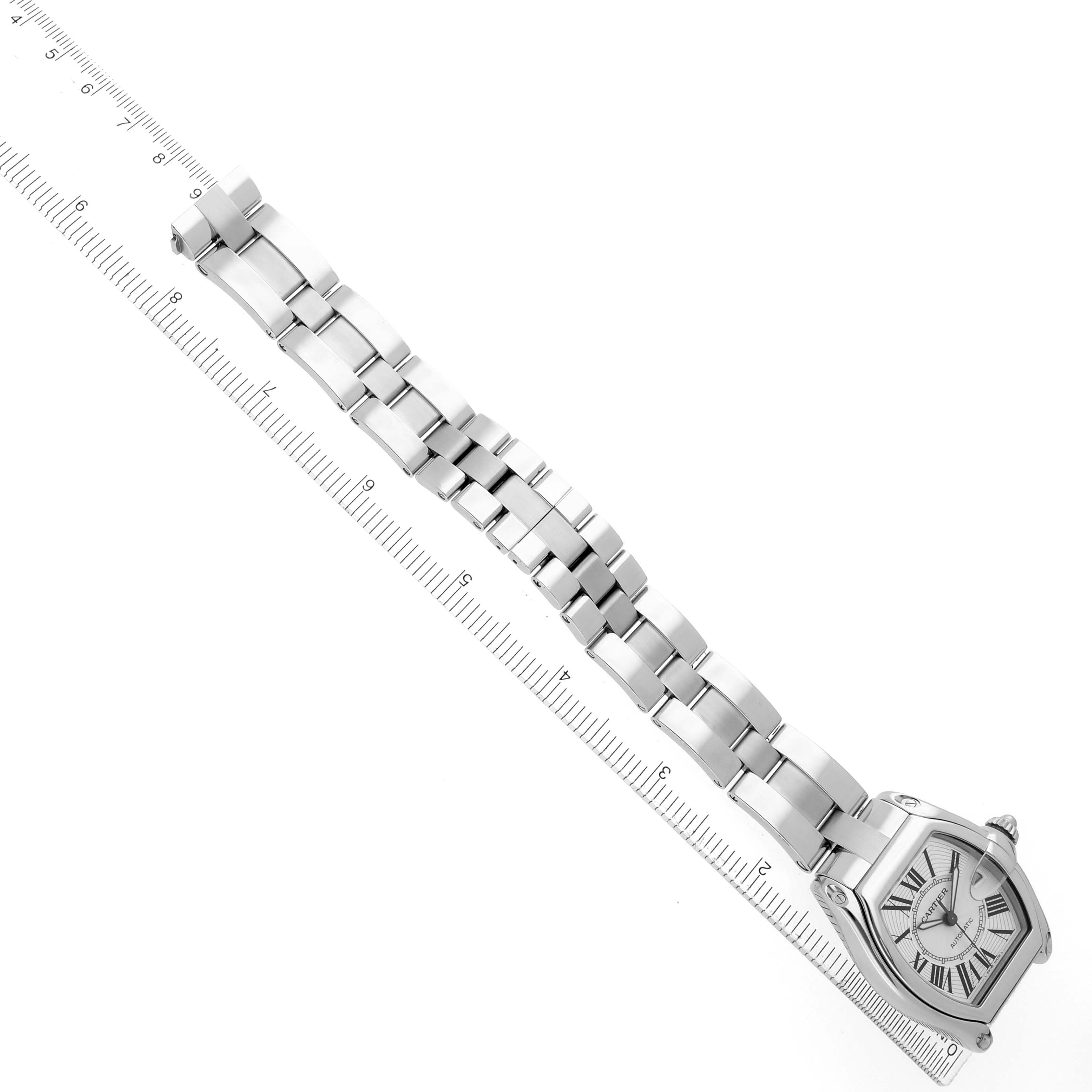 The Cartier Roadster W62025V3 Men's Stainless Steel Silver Dial watch is shown at an angled top view, displaying the case and full bracelet alongside a ruler.