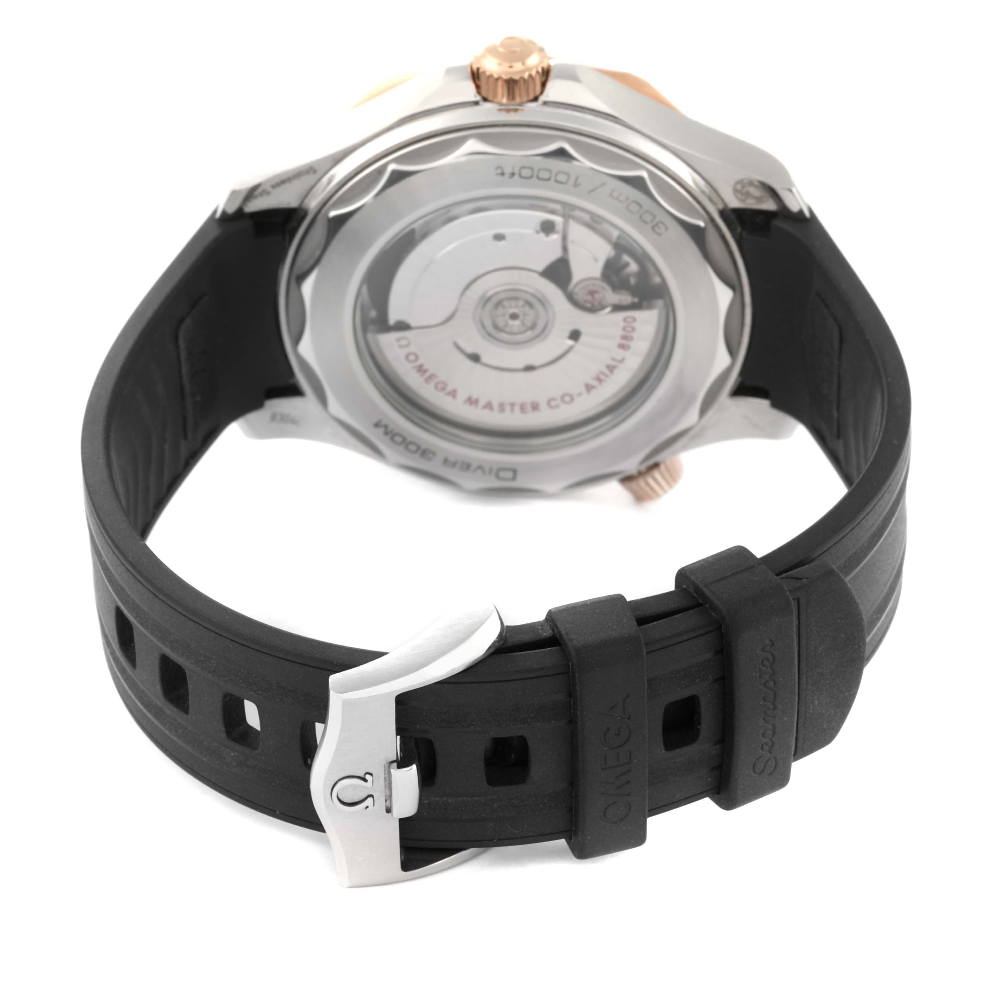 The image shows the back of an Omega Seamaster 210.22.42.20.01.002 Men's Steel and Gold (two tone) Black Dial watch featuring its exhibition case back and rubber strap with a clasp.