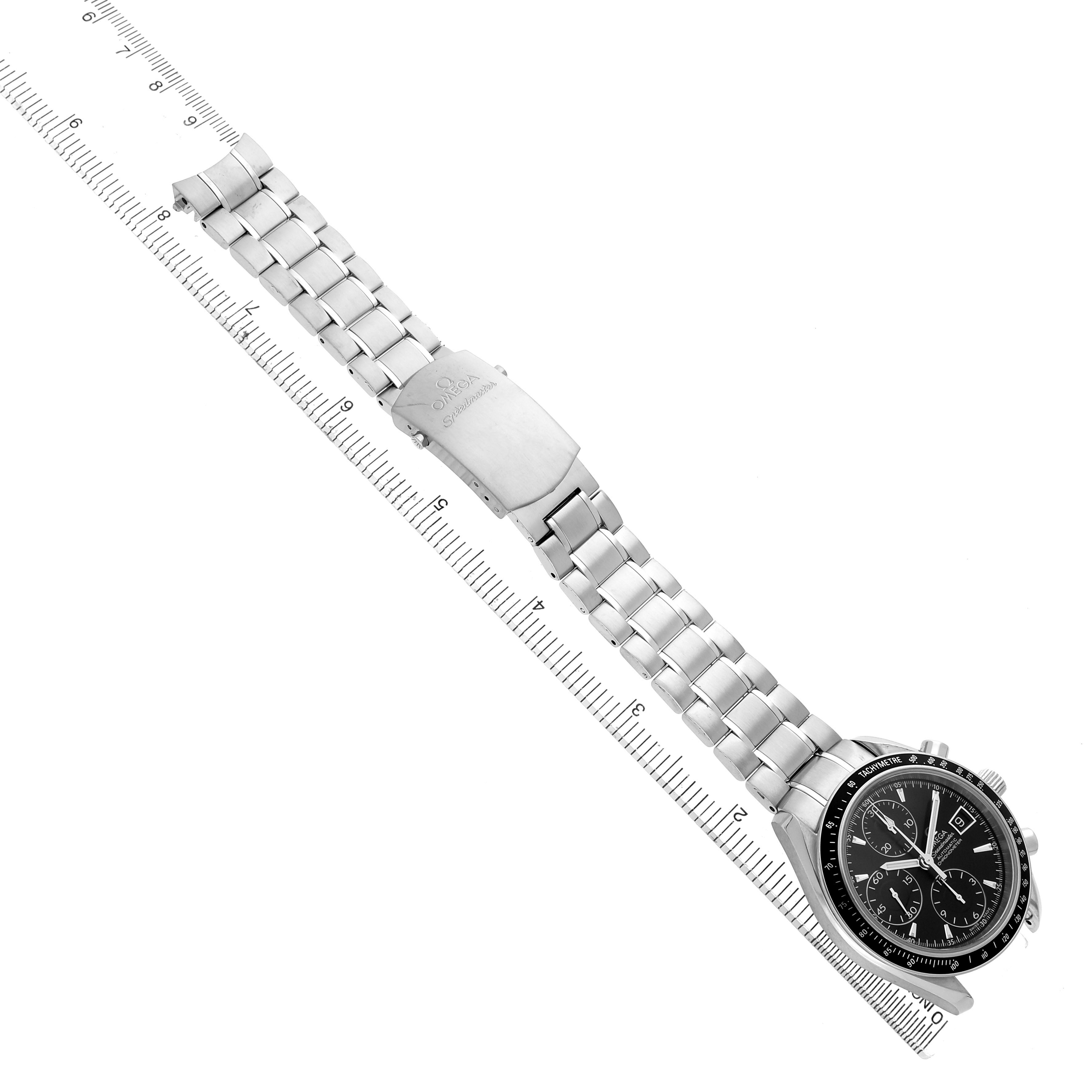 The Omega Speedmaster 3210.50.00 Men's Stainless Steel Black Dial watch is shown from a top angle, displaying the face, metal bracelet, and clasp alongside a measuring ruler.