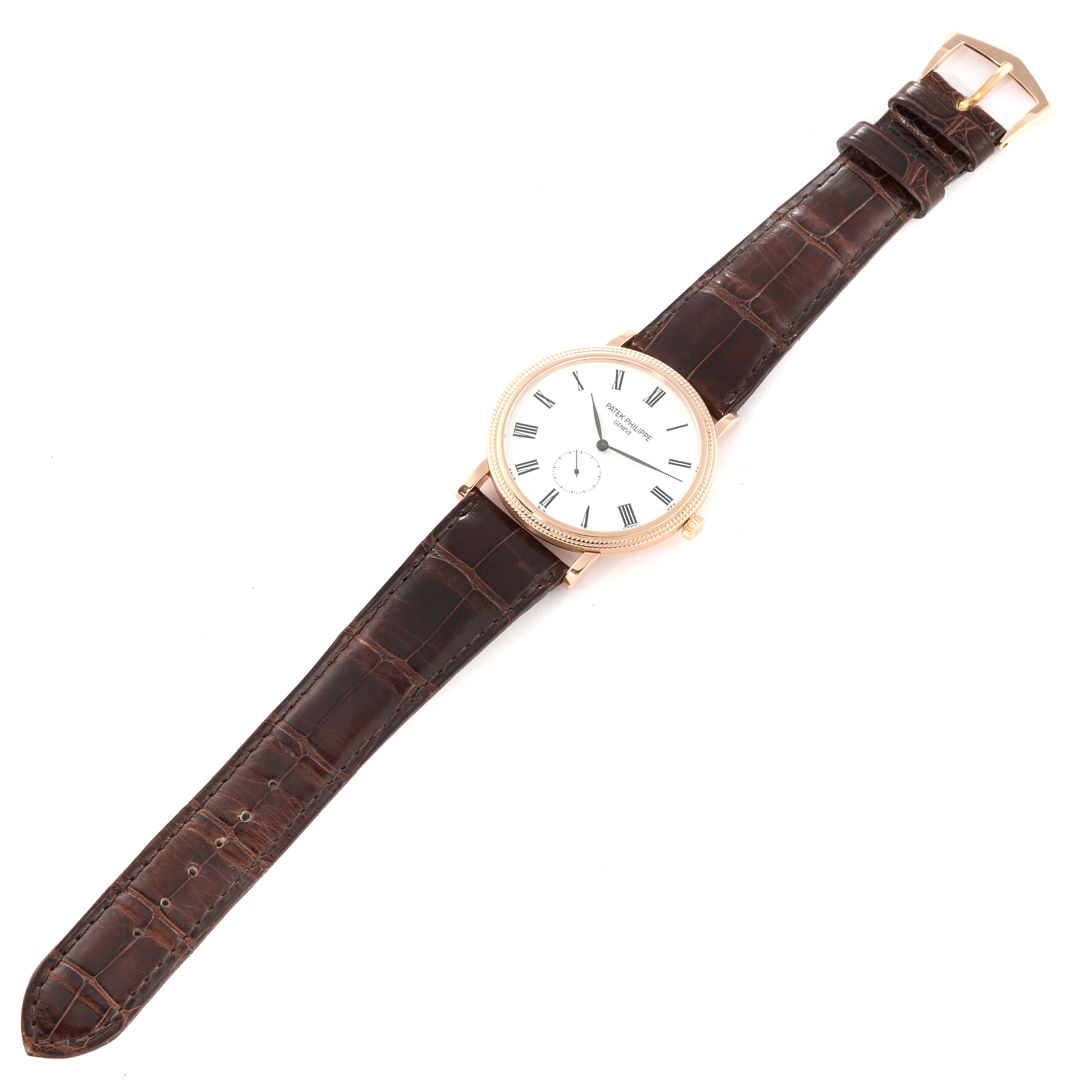 The image shows a top-down view of a Patek Philippe Calatrava 5119R Men
s Rose Gold White Dial 5119R Men
s Rose Gold White Dial watch featuring a white dial and a brown leather strap.