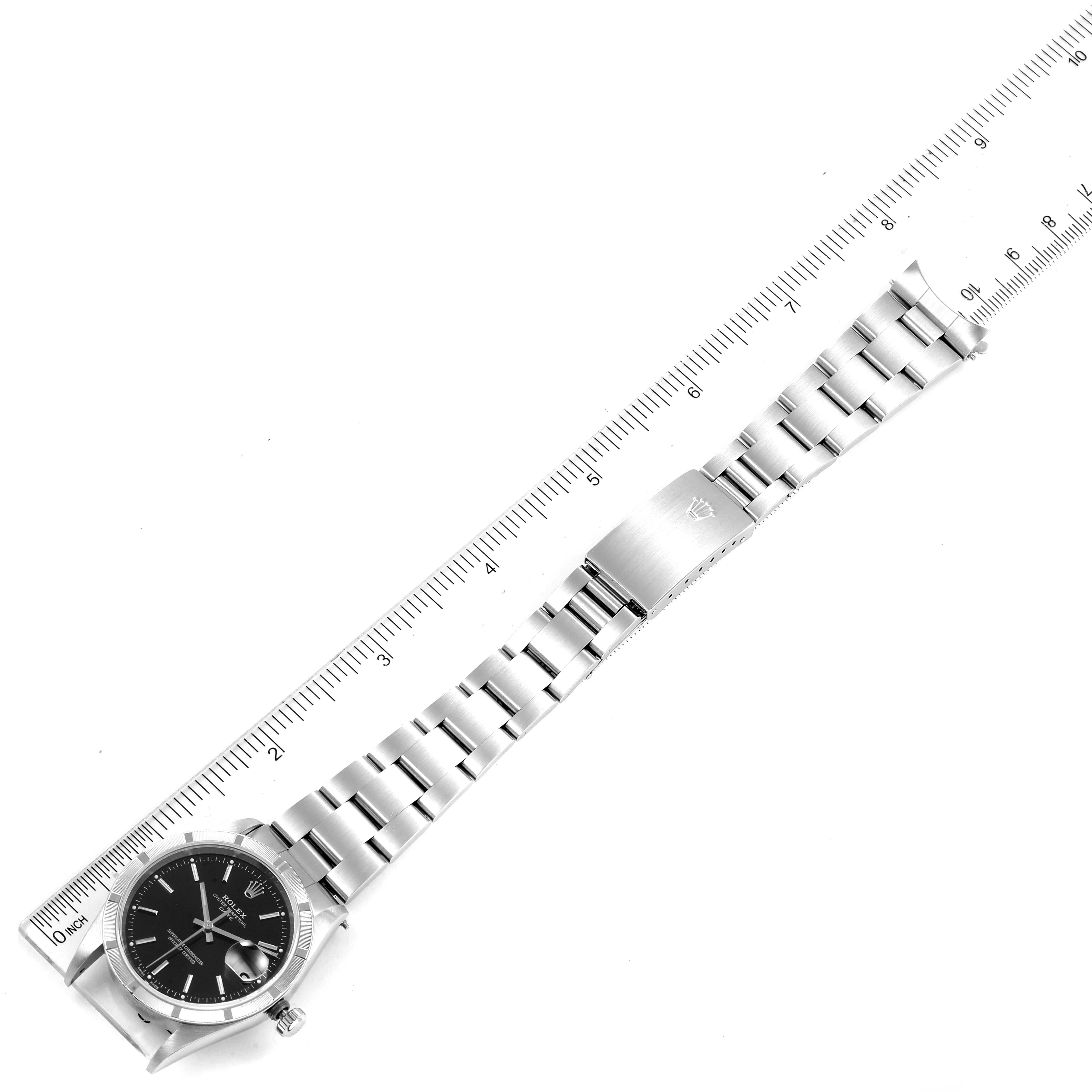 The image shows a top view of the Rolex Date 15210 Men's Stainless Steel Black Dial 15210 Men's Stainless Steel Black Dial model, featuring its watch face, band, and clasp beside a ruler.