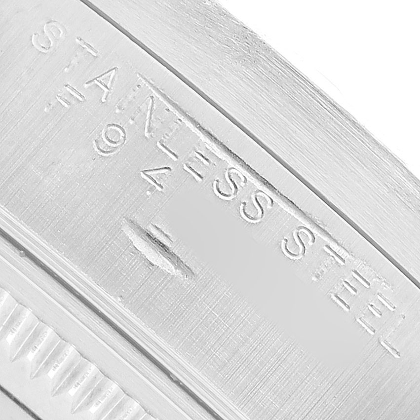 The image shows a close-up of a stainless steel marking on the casing, likely part of the Rolex Date 15210 Men's Stainless Steel White Dial model.