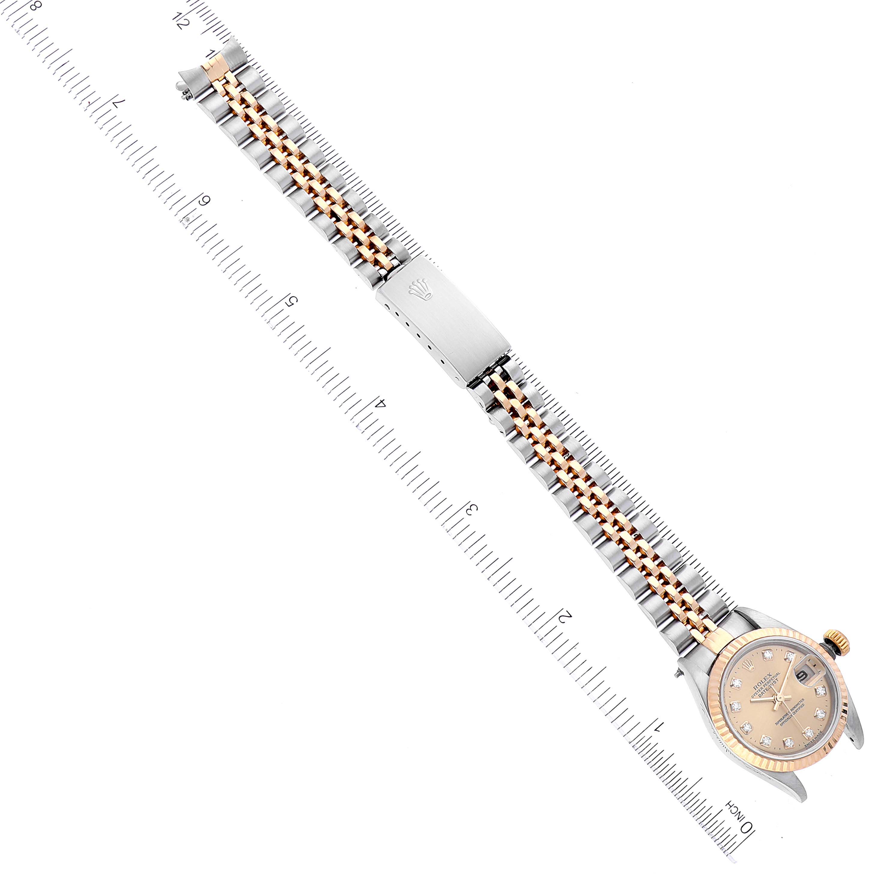 The Rolex Datejust 79173 Women's Stainless Steel Champagne Dial watch is shown at an angled top view, highlighting the bracelet and case near a measuring ruler.