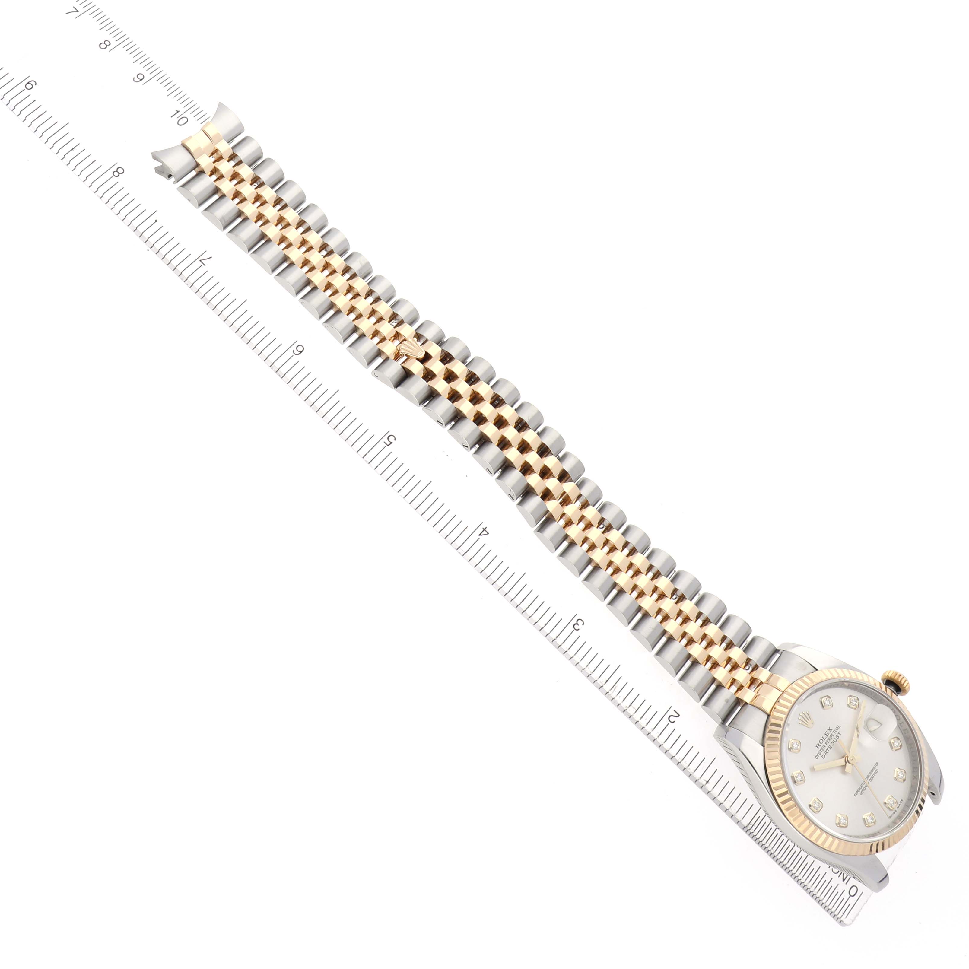 The Rolex Datejust 116233 Men's Steel and Gold (two tone) Silver Dial watch is shown from a top view, featuring the case, dial, and a two-tone bracelet lying beside a ruler.