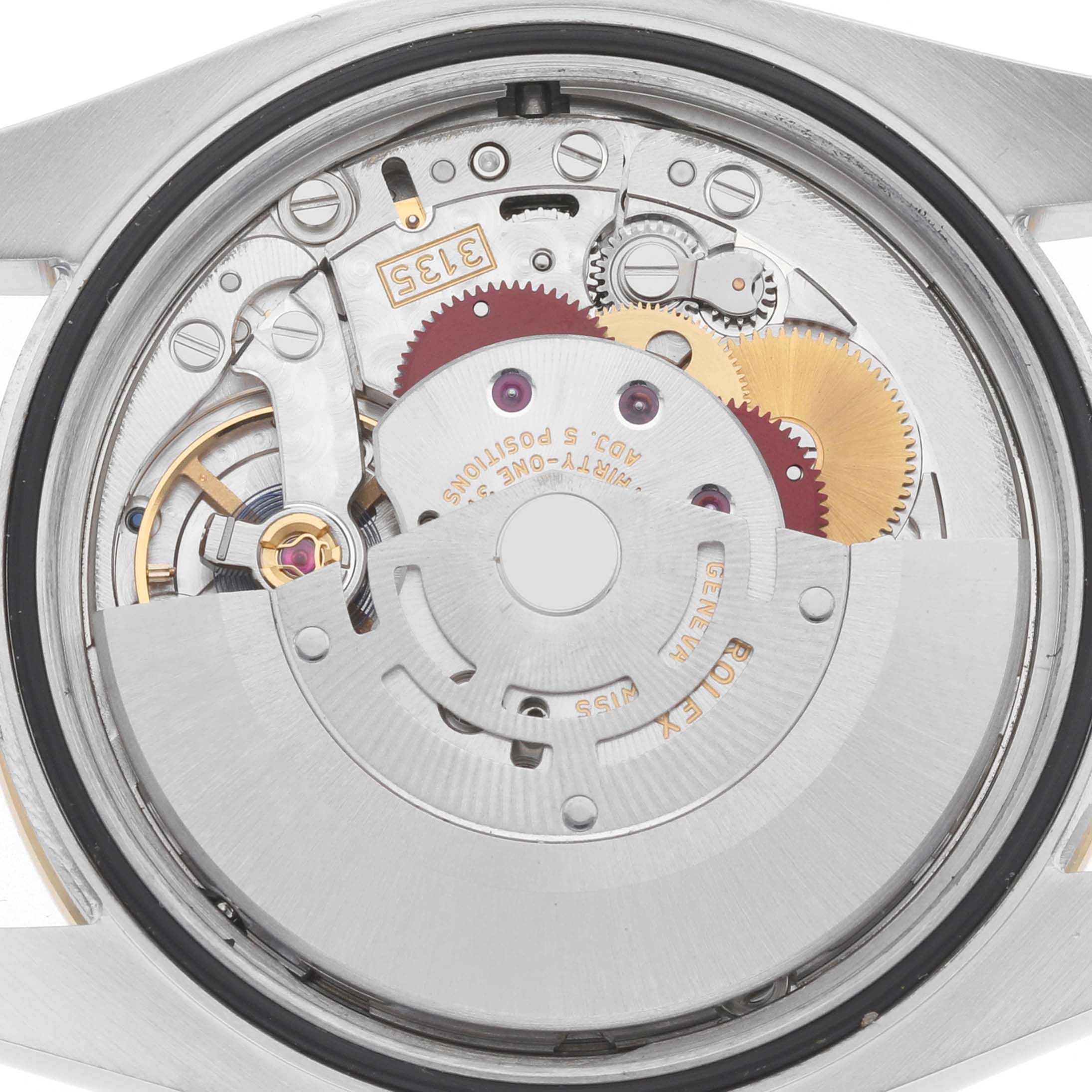 The image shows the movement of a Rolex Datejust 116243 Men's Steel and Gold (two tone) Silver Dial from a rear angle, highlighting gears and mechanical components.