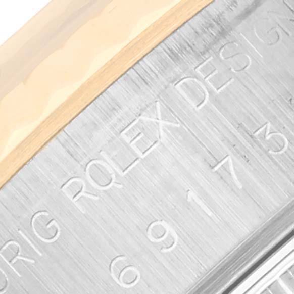 The image shows an angled close-up of the Rolex Datejust 69173 Women's Steel and Gold (two tone) White Dial 69173 Women's Steel and Gold (two tone) White Dial model's polished metal side with engraved text.