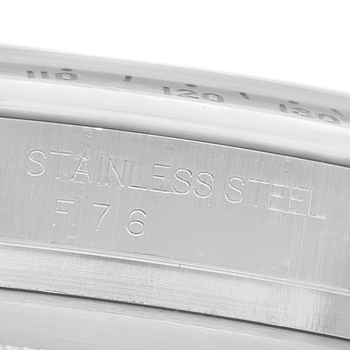 The image shows a close-up of the engravings on the stainless steel case of a Rolex Daytona 116520 Men's Stainless Steel White Dial watch.