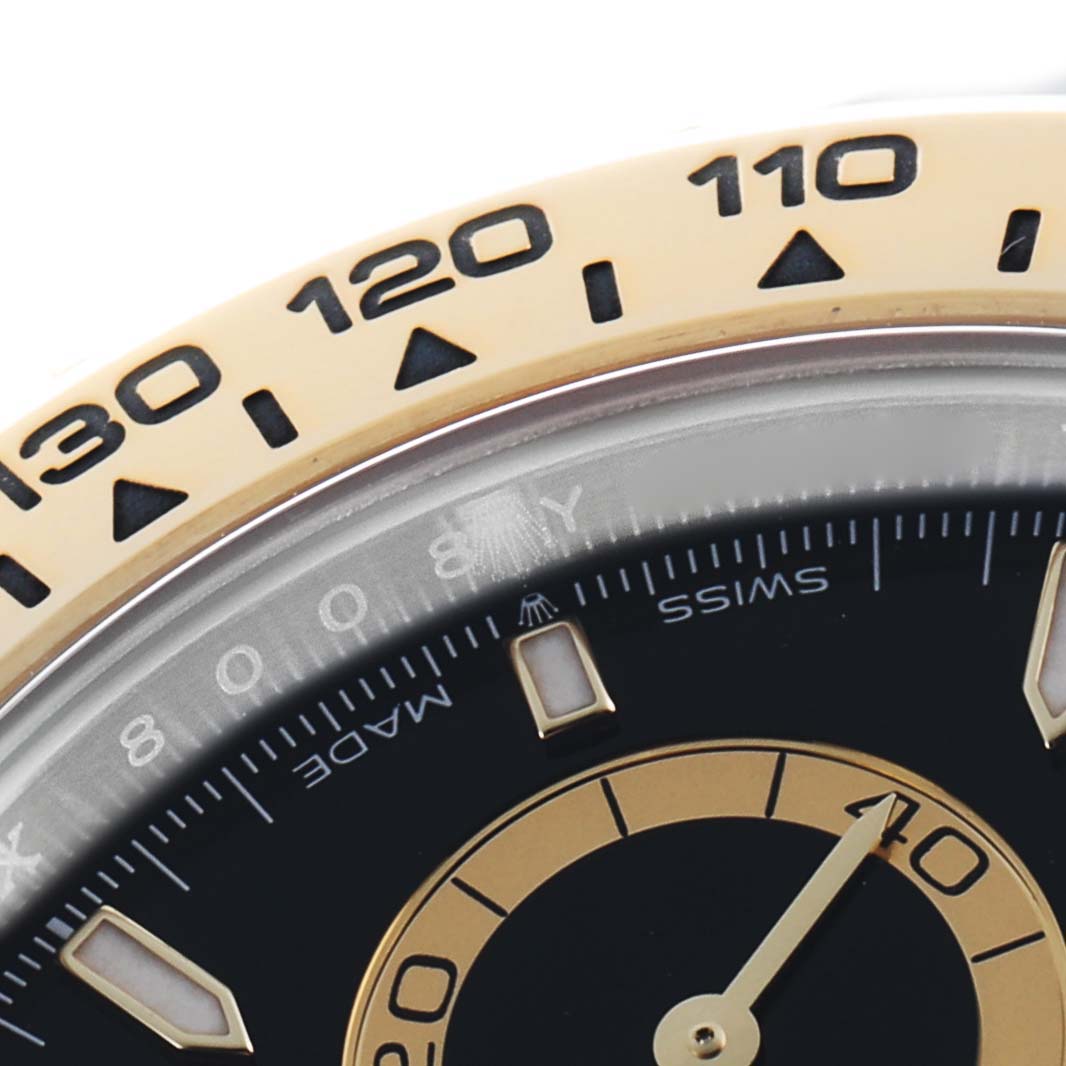 The image shows a close-up of the upper portion of the Rolex Daytona 126503 Men's Steel and Gold (two tone) Black Dial watch bezel and part of the dial.