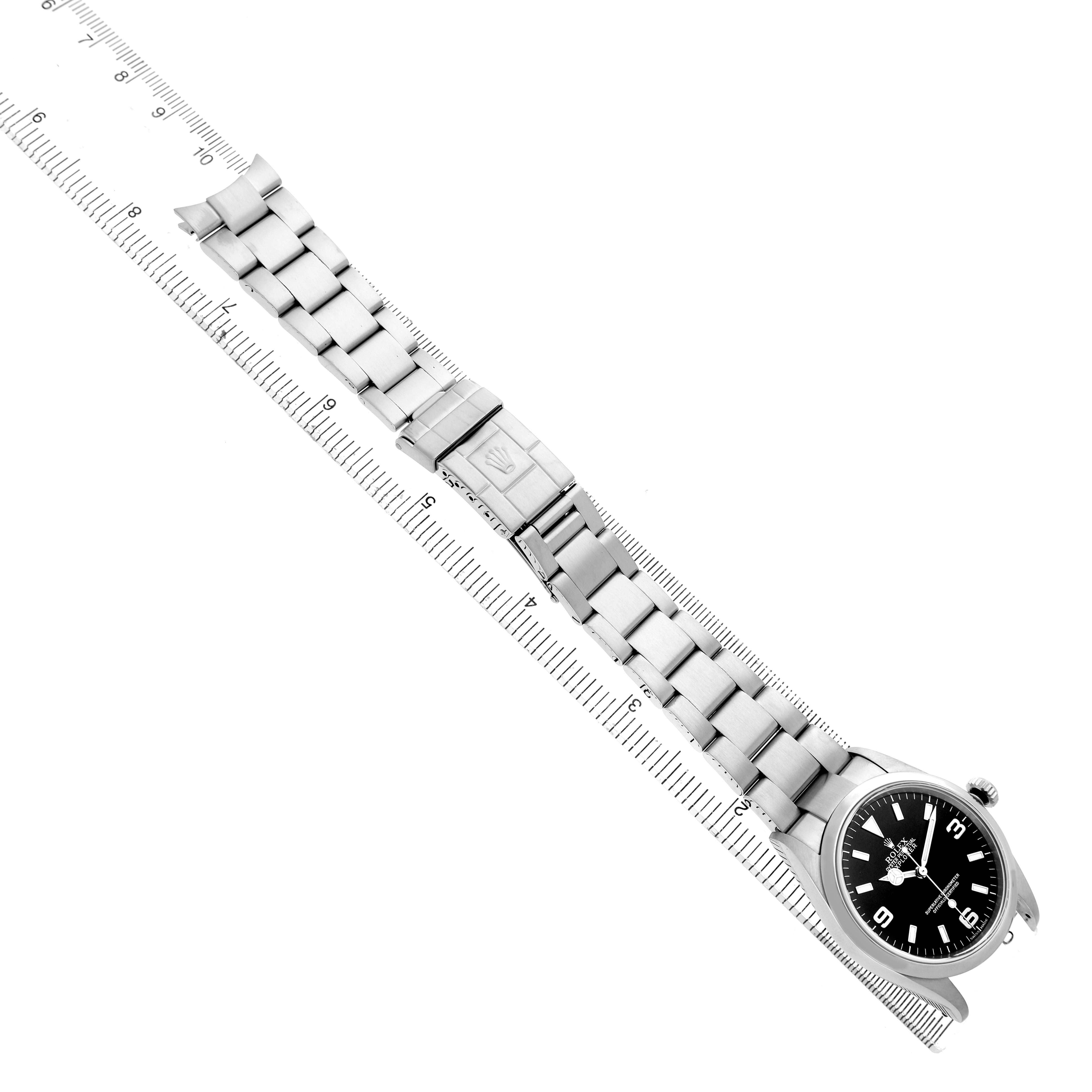 The image shows the Rolex Explorer 114270 Men's Stainless Steel Black Dial watch from a top-down angle, displaying the full bracelet and clasp aligned with a ruler.