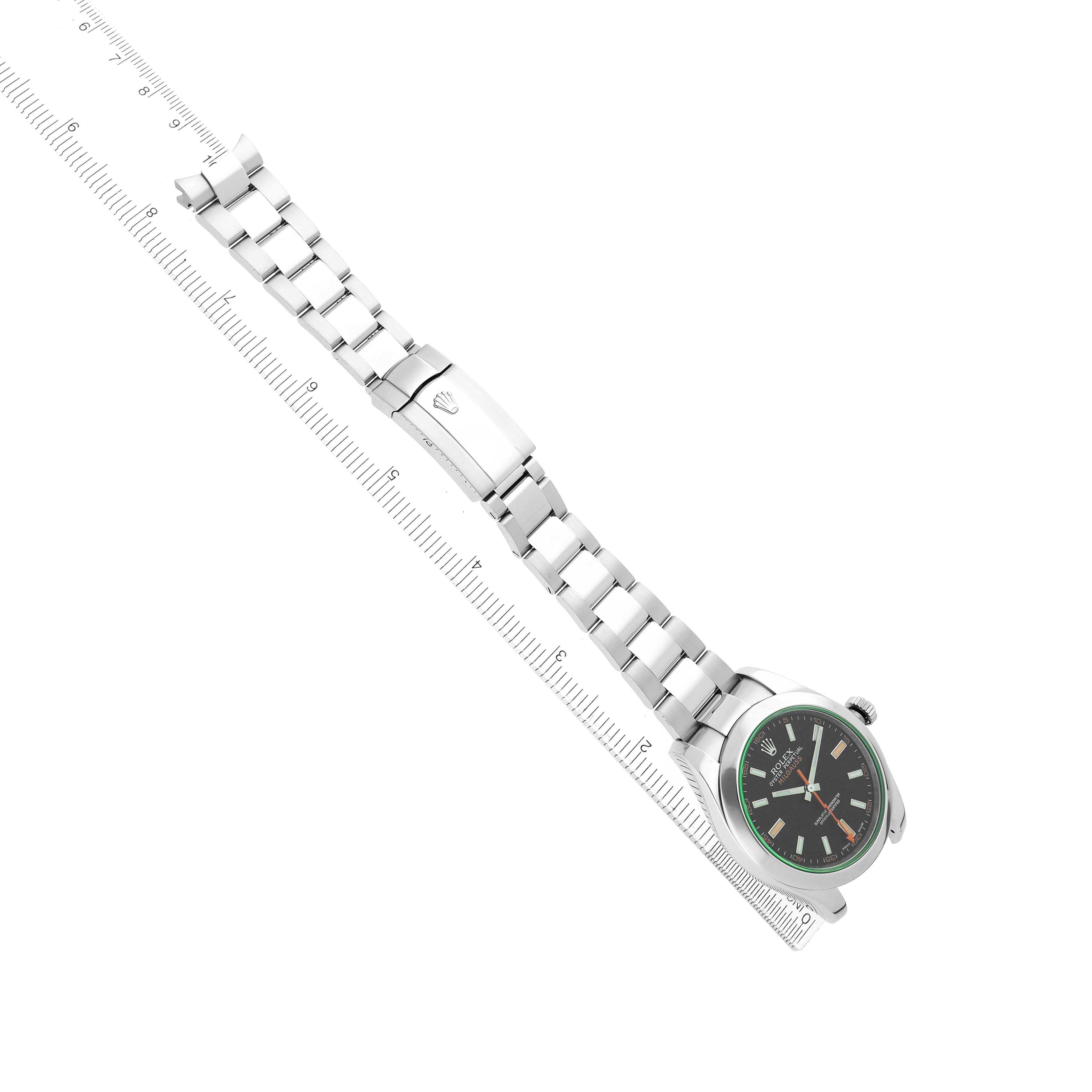 The Rolex Milgauss 116400GV Men's Stainless Steel Black Dial watch is shown laid flat with the face, bracelet, and clasp visible, positioned alongside a ruler for scale.