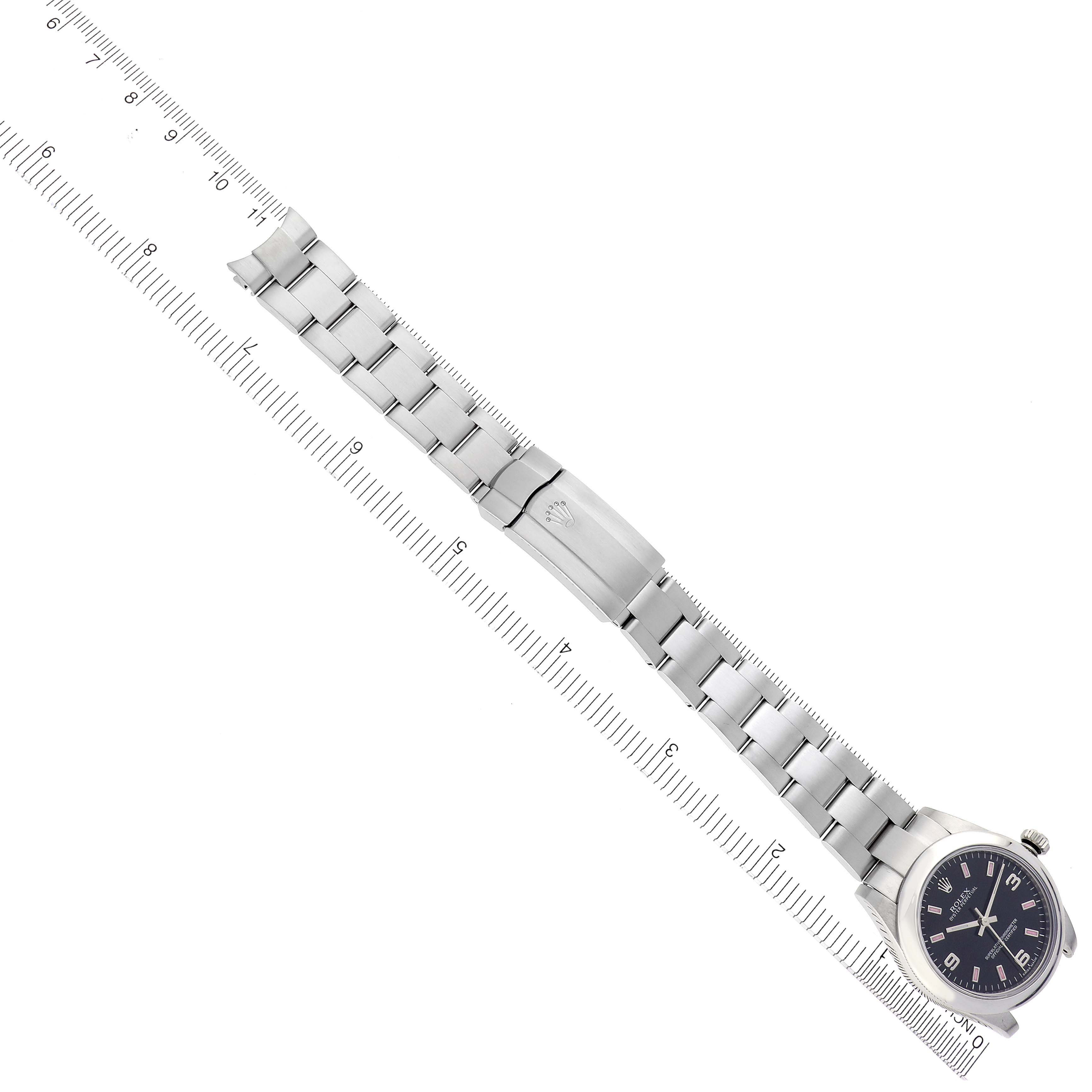 The image shows the Rolex Mid-Size 177200 Women's Stainless Steel Black Dial 177200 Women's Stainless Steel Black Dial watch from a top-down angle, displaying the full face and metal bracelet alongside a ruler.