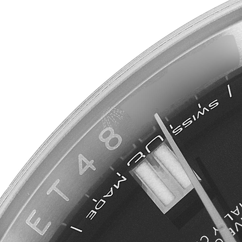 The image shows a close-up of the dial and glass of a Rolex Oyster Perpetual 116000 Men
s Stainless Steel Black Dial 116000 Men
s Stainless Steel Black Dial watch at an angled view.