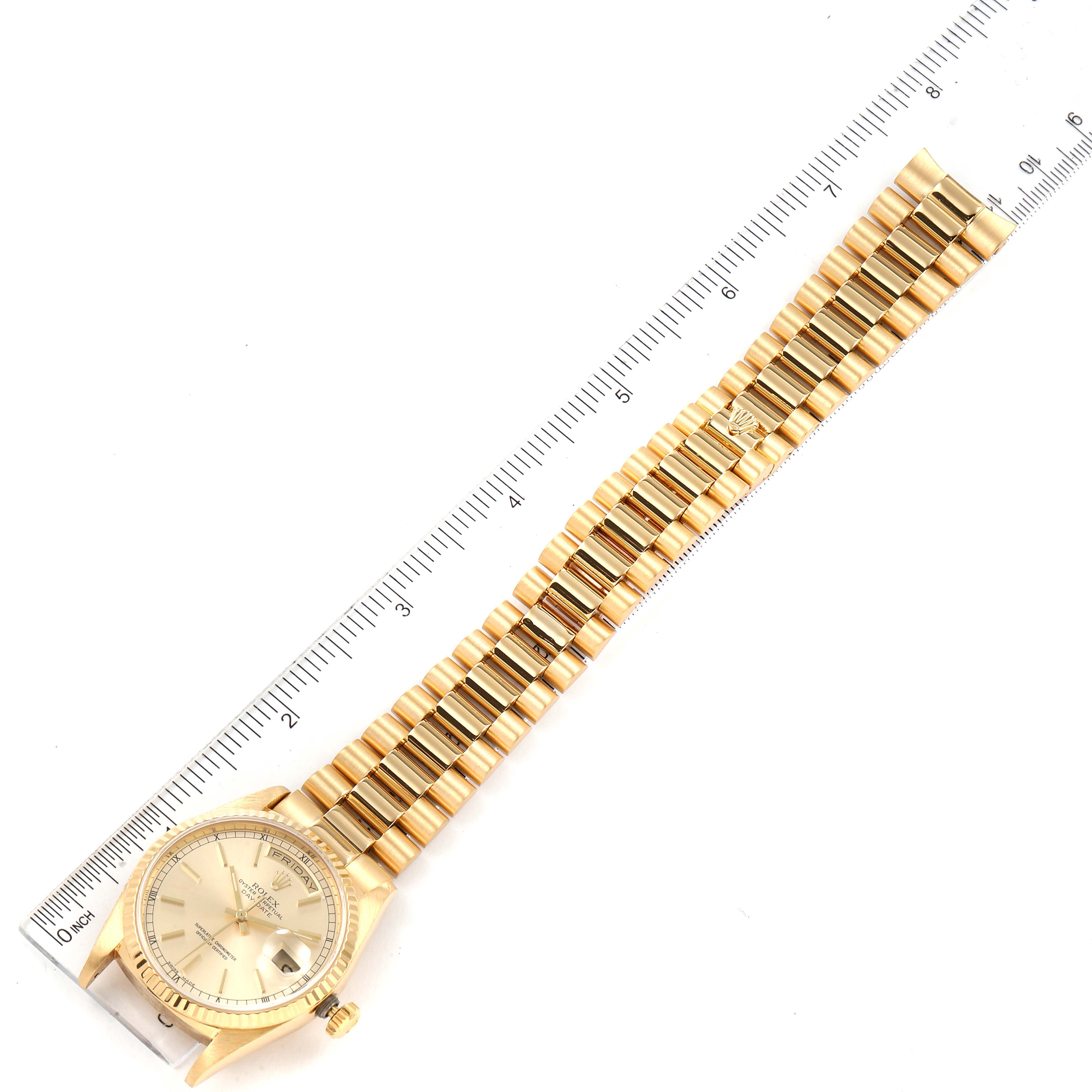 The Rolex President 18238 Men
s Yellow Gold Champagne Dial 18238 Men
s Yellow Gold Champagne Dial watch is shown from a top-down angle with its face and bracelet alongside a ruler.