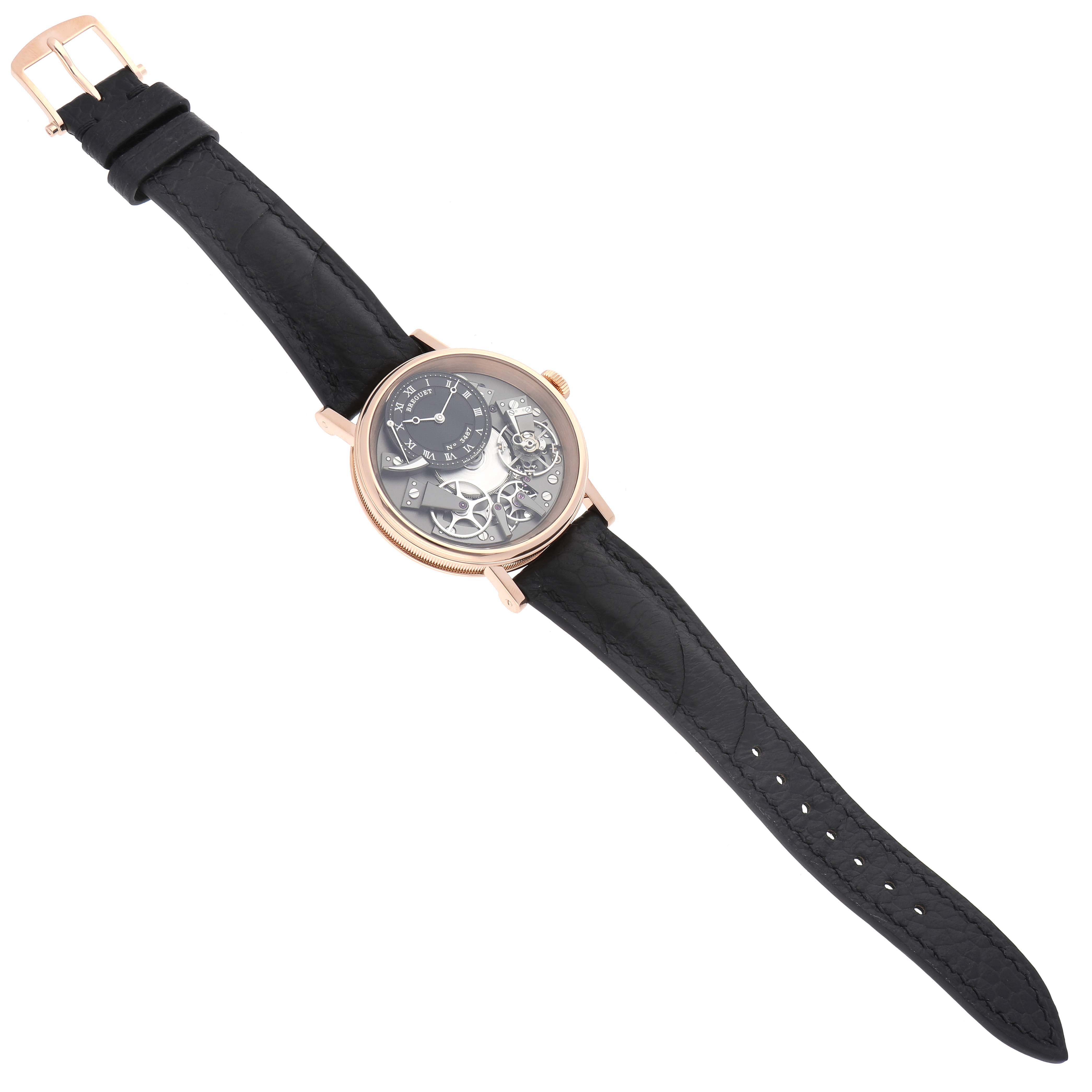 The Breguet Tradition 7057BR/G9/9W6 Men's Rose Gold Silver Dial 7057BR/G9/9W6 Men's Rose Gold Silver Dial watch is shown from an angled top view, revealing the face, mechanical details, and black strap.