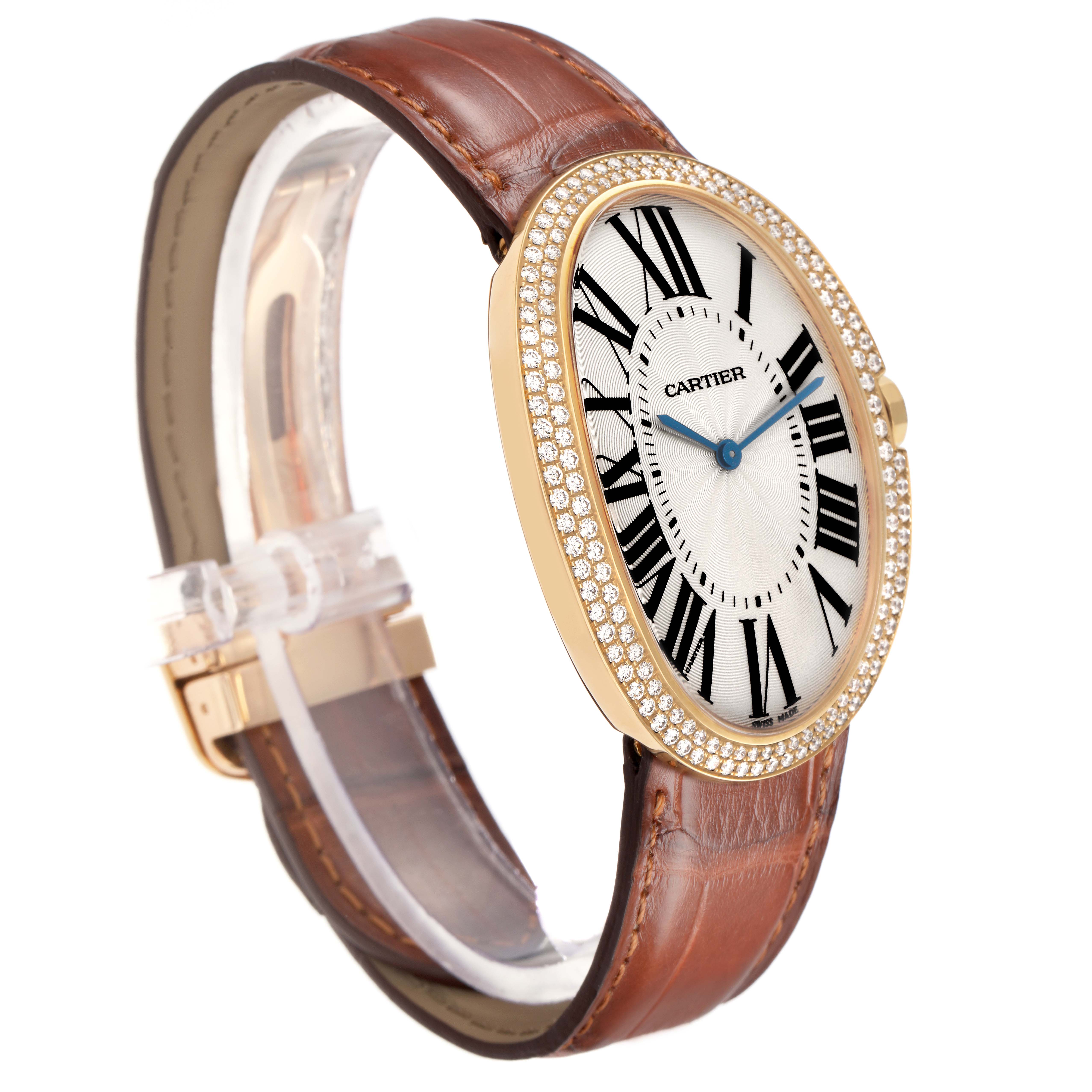 The Cartier Baignoire WB520005 Women
s Yellow Gold Silver Dial watch is shown at an angle displaying its oval face, Roman numerals, leather strap, and diamond bezel.