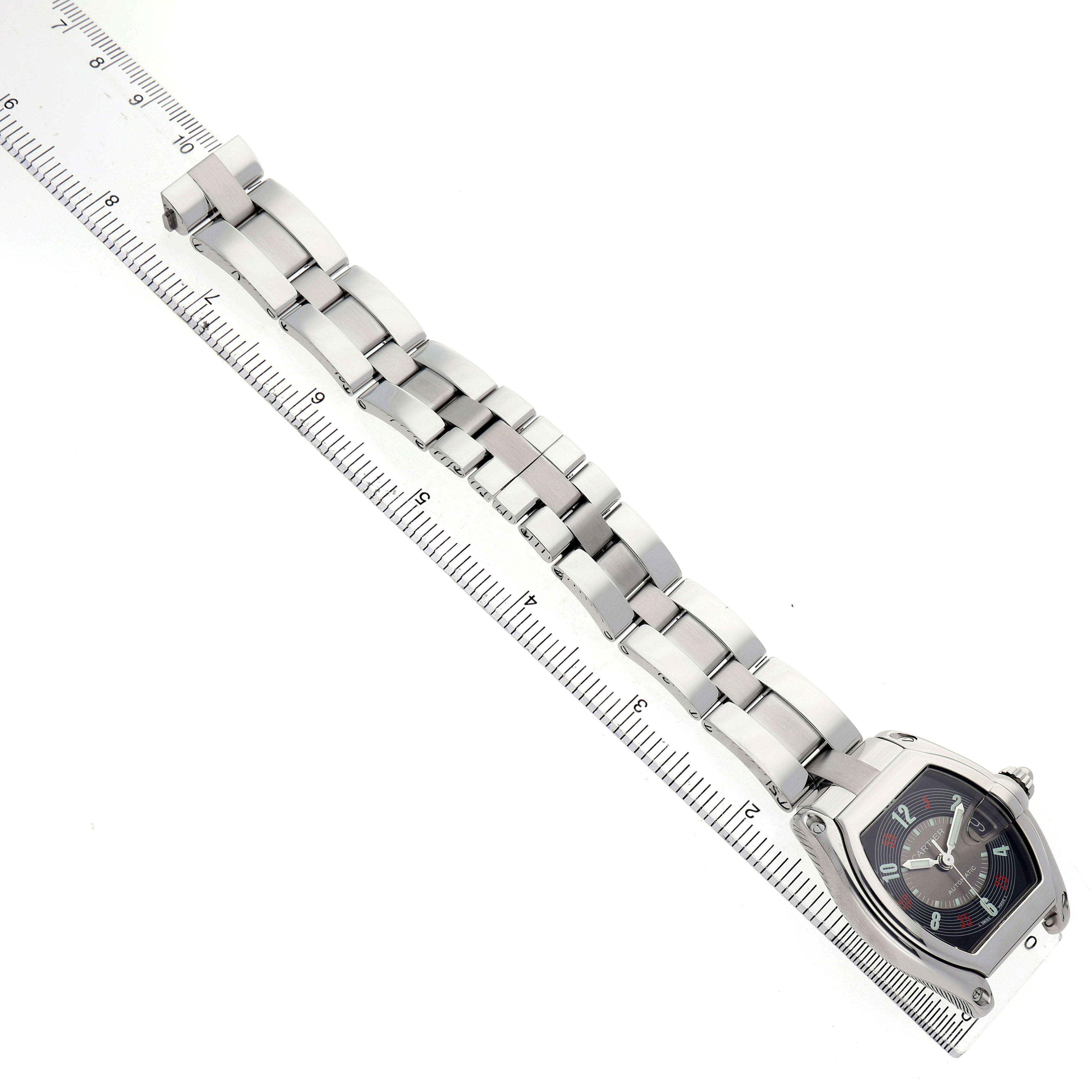The Cartier Roadster W62002V3 Men's Stainless Steel Black Dial watch is shown at an angled view with the full bracelet and a ruler beneath for scale reference.