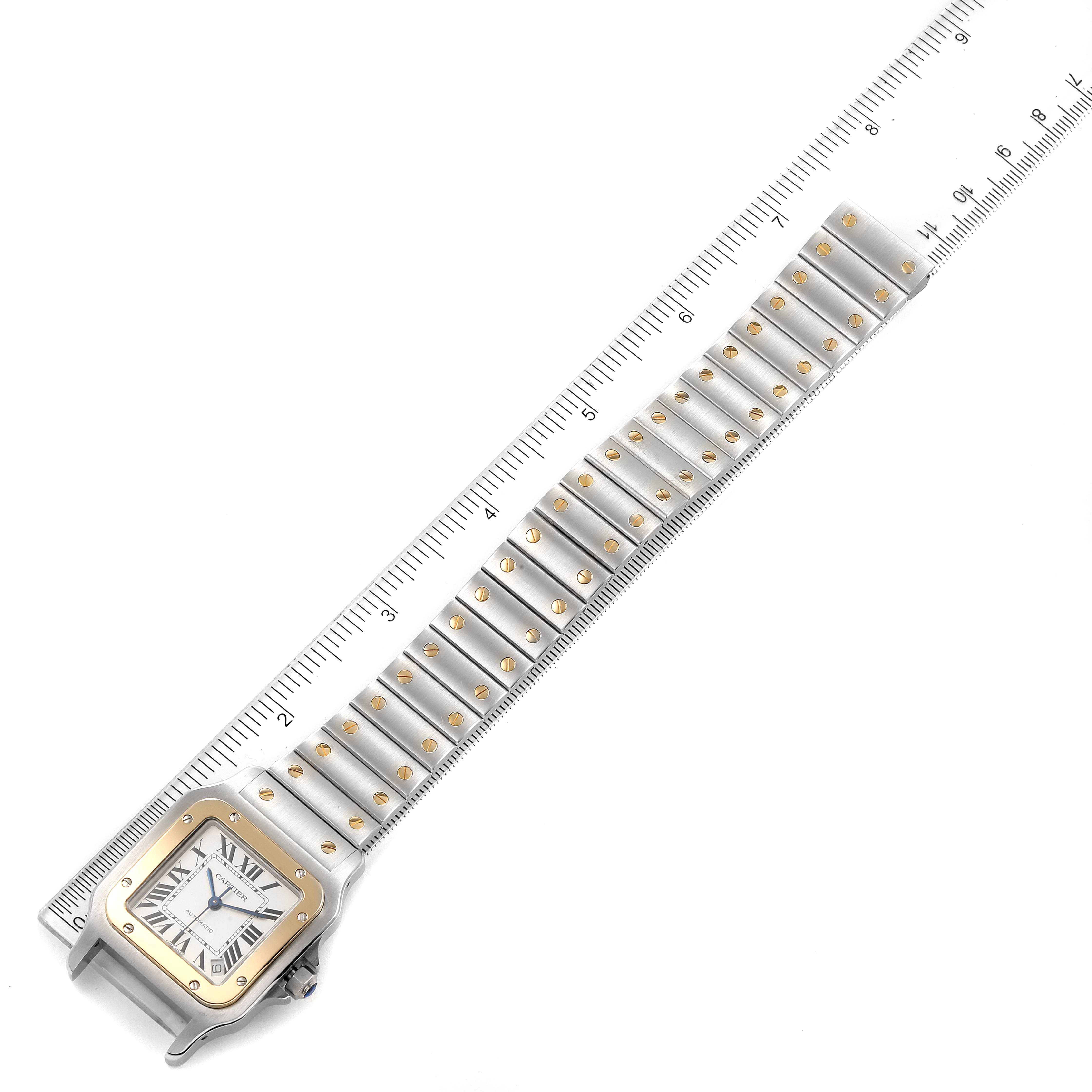 This image shows a top-down view of the Cartier Santos W20099C4 Men
s Steel and Gold (two tone) Silver Dial W20099C4 Men
s Steel and Gold (two tone) Silver Dial watch, displaying the face and full length of the band next to a ruler.