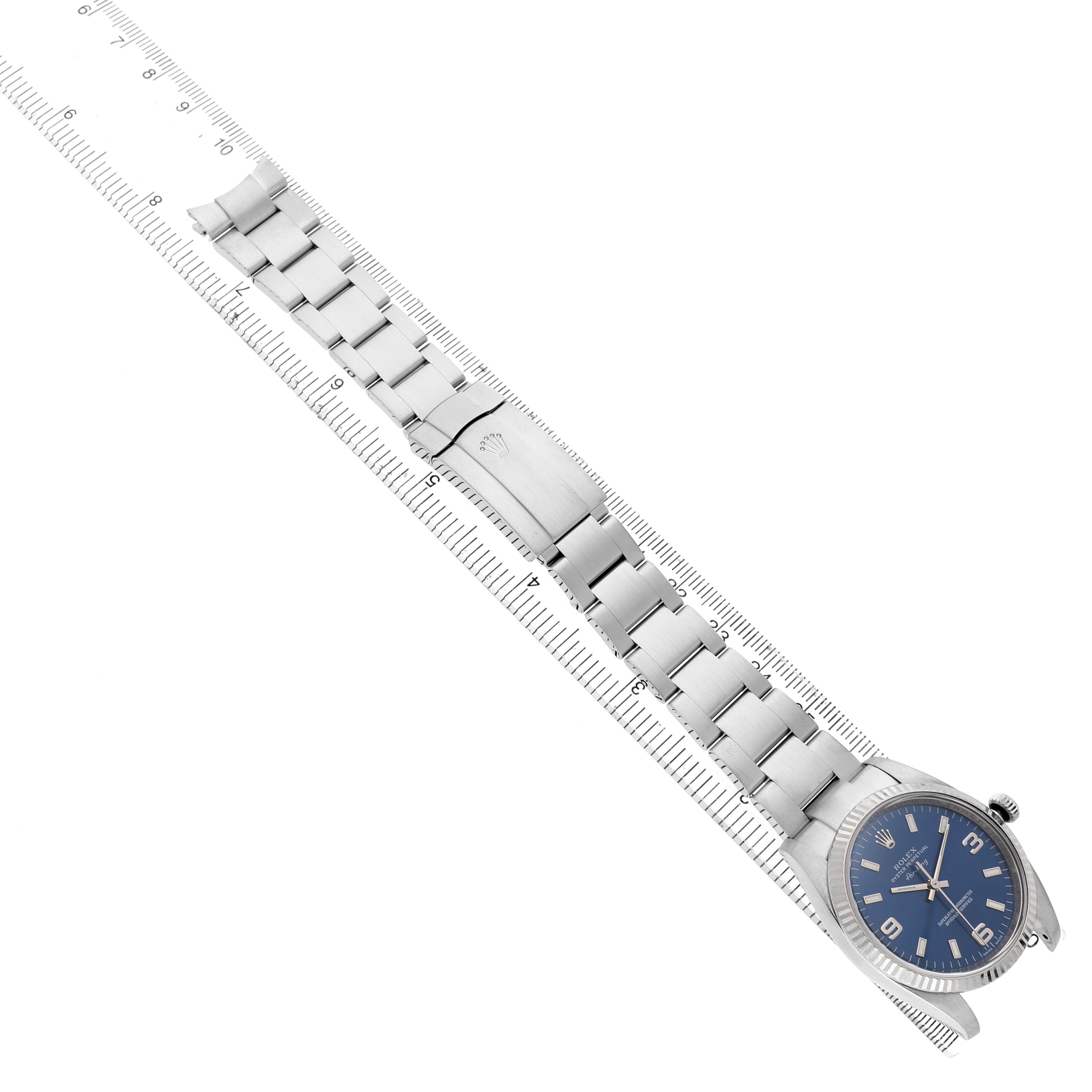 The Rolex Air-King 114234 Men's Stainless Steel Blue Dial watch is shown diagonally with a clear view of its bracelet and clasp against a ruler for scale.