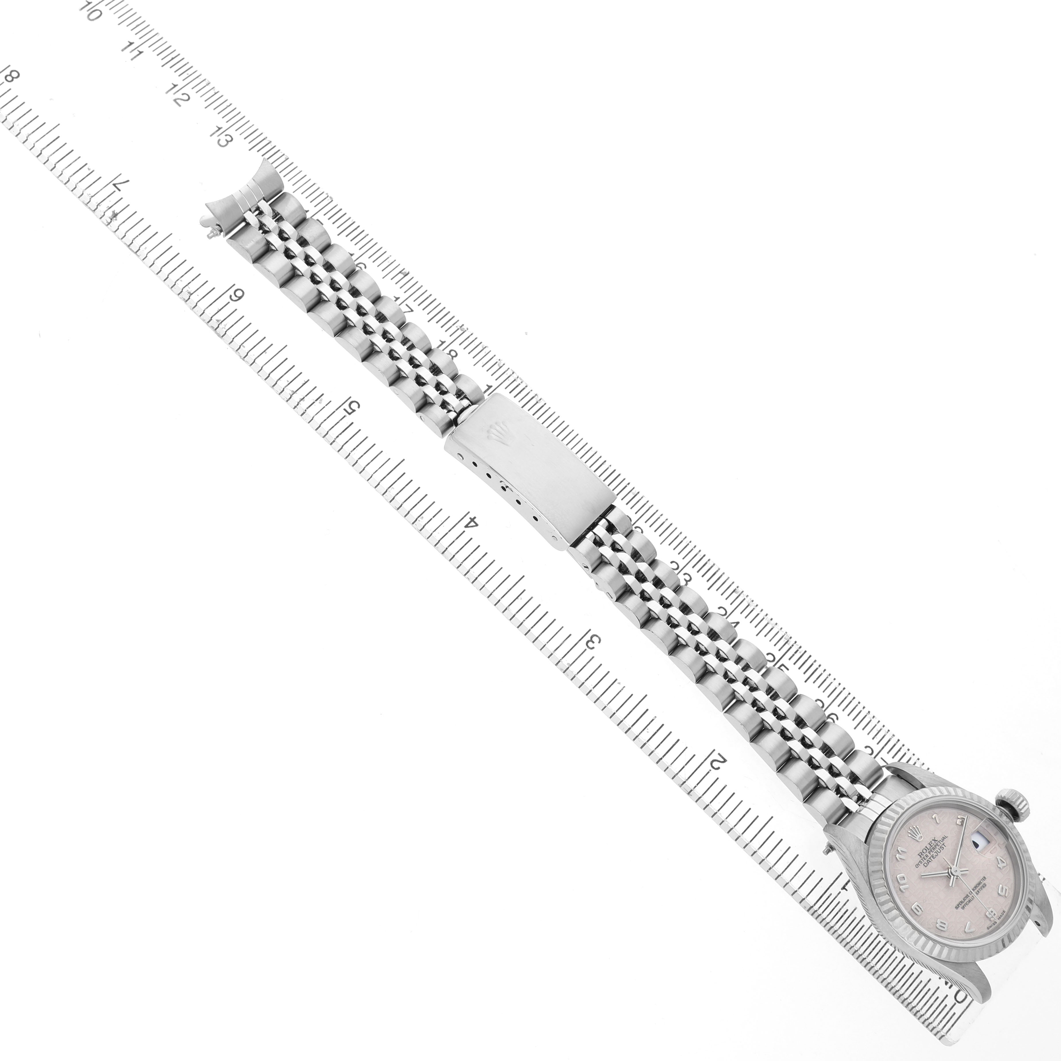 The Rolex Datejust 79174 Women's Stainless Steel White Dial watch is shown at a diagonal angle with its dial, bracelet, and clasp visible, resting on a ruler.