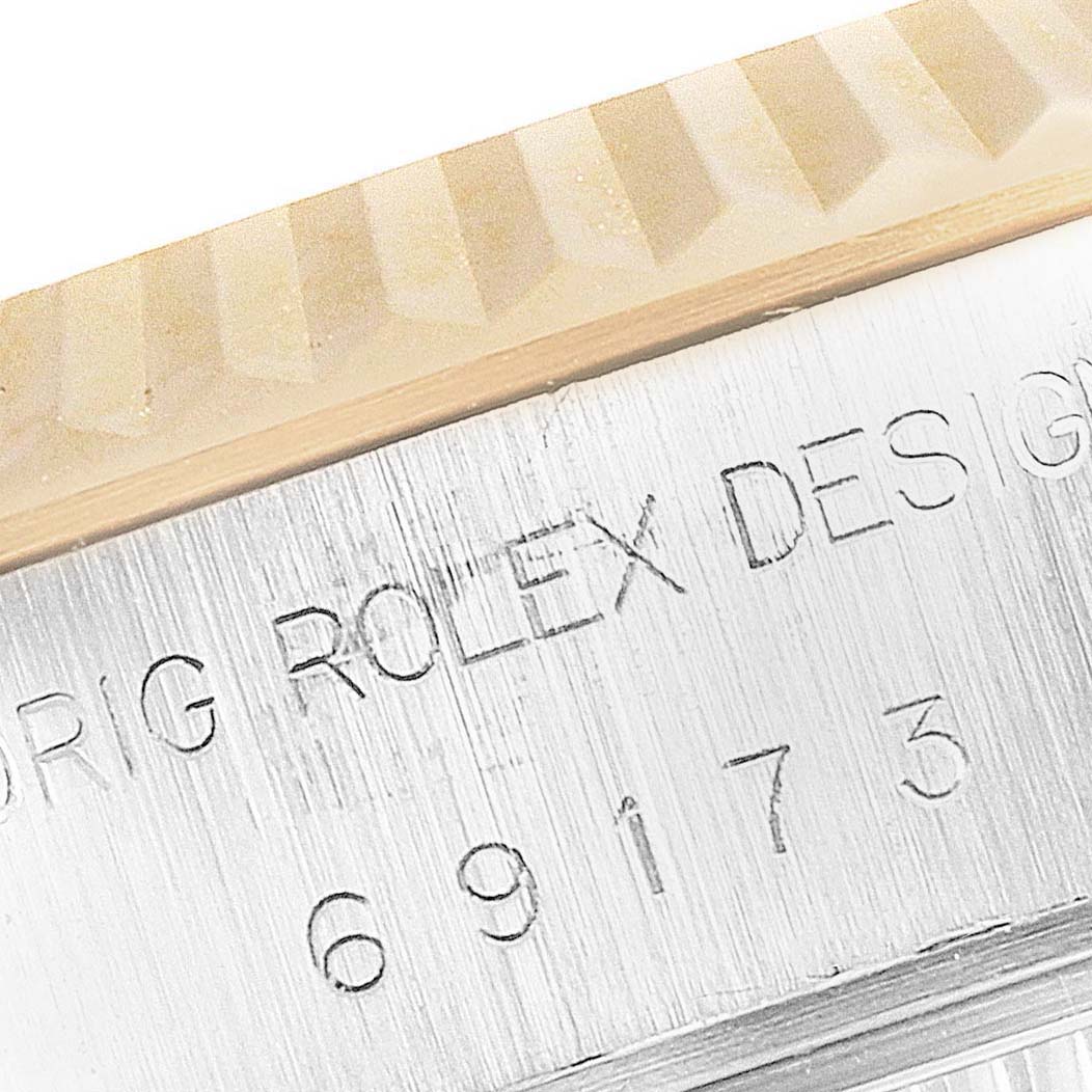 This image shows a close-up of the Rolex Datejust 69173 Women's Steel and Gold (two tone) Champagne Dial 69173 Women's Steel and Gold (two tone) Champagne Dial watch bezel and part of the serial number engraving.