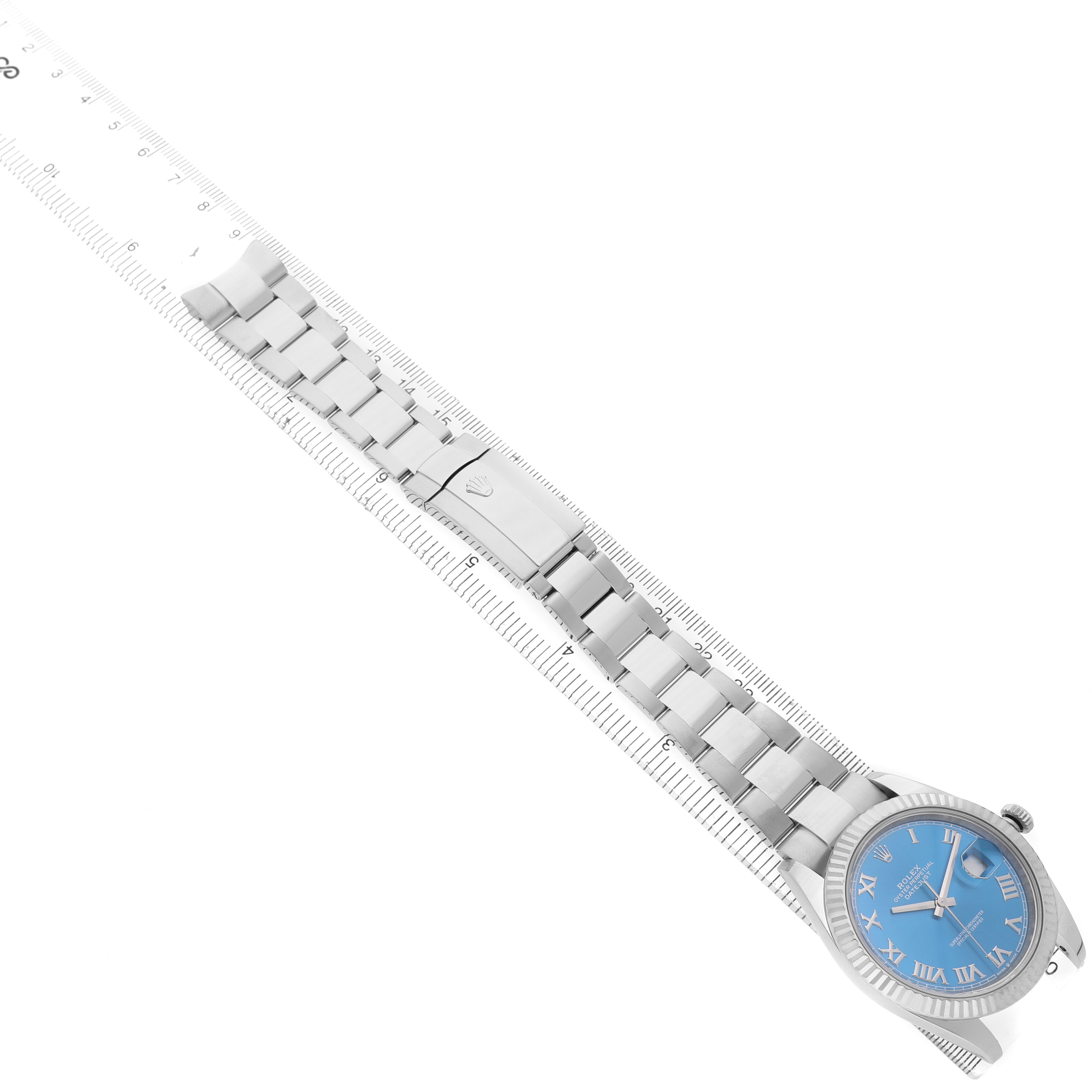 The Rolex Datejust 41 126334 Men's Stainless Steel Blue Dial watch is shown from above, displaying its blue dial, bracelet, and clasp, alongside a ruler for scale.