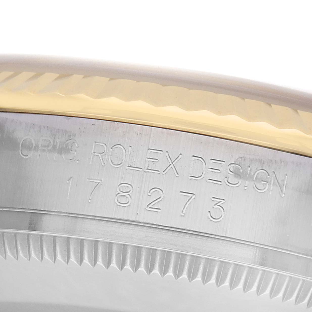 The image shows a close-up of the side of a Rolex Mid-Size 178273 Women's Steel and Gold (two tone) White Dial watch, featuring the engraved serial number and part of the bezel.