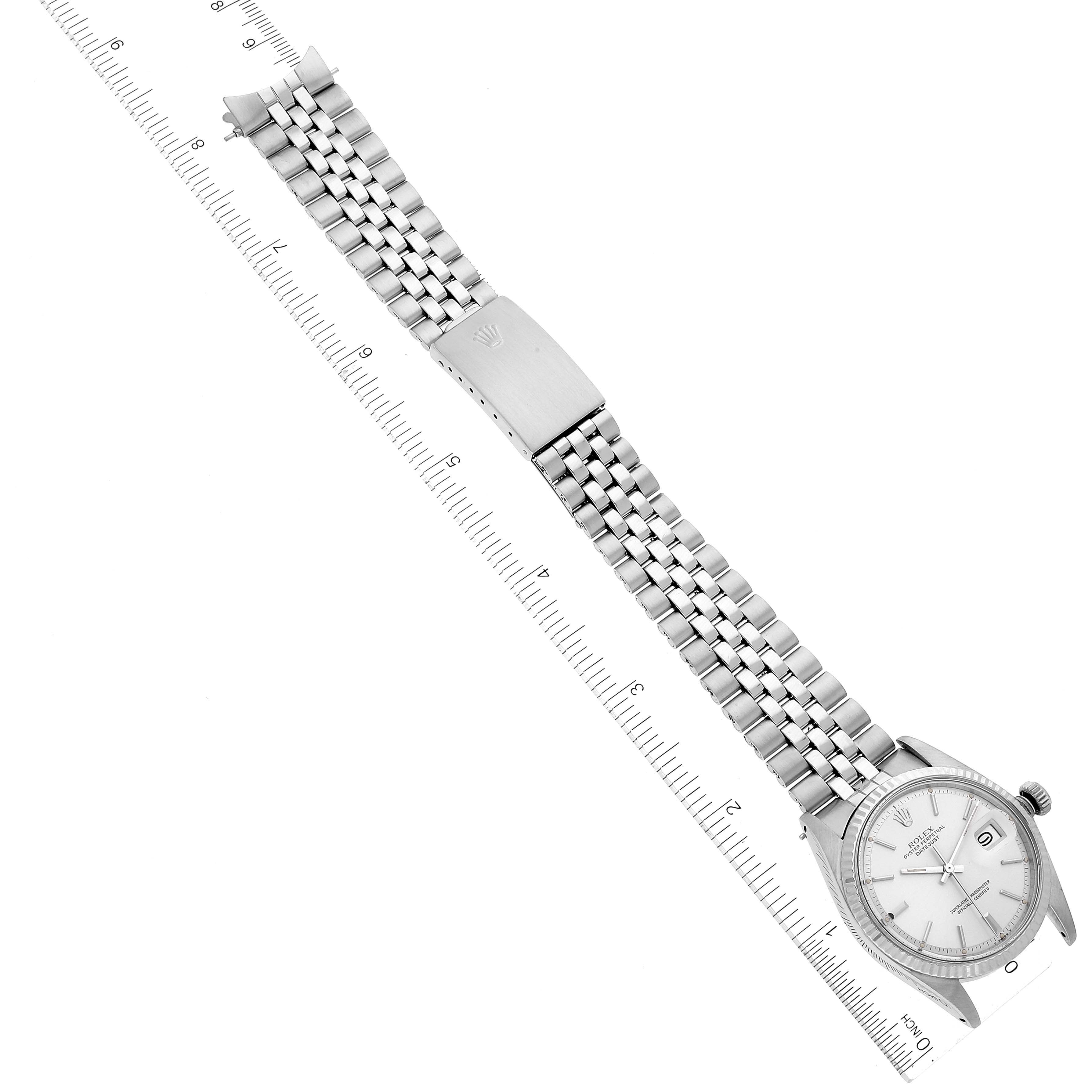 The image shows an overhead view of a Rolex Vintage Collection 1601 Men
s Stainless Steel Silver Dial 1601 Men
s Stainless Steel Silver Dial watch and its stainless steel band, placed next to a ruler.