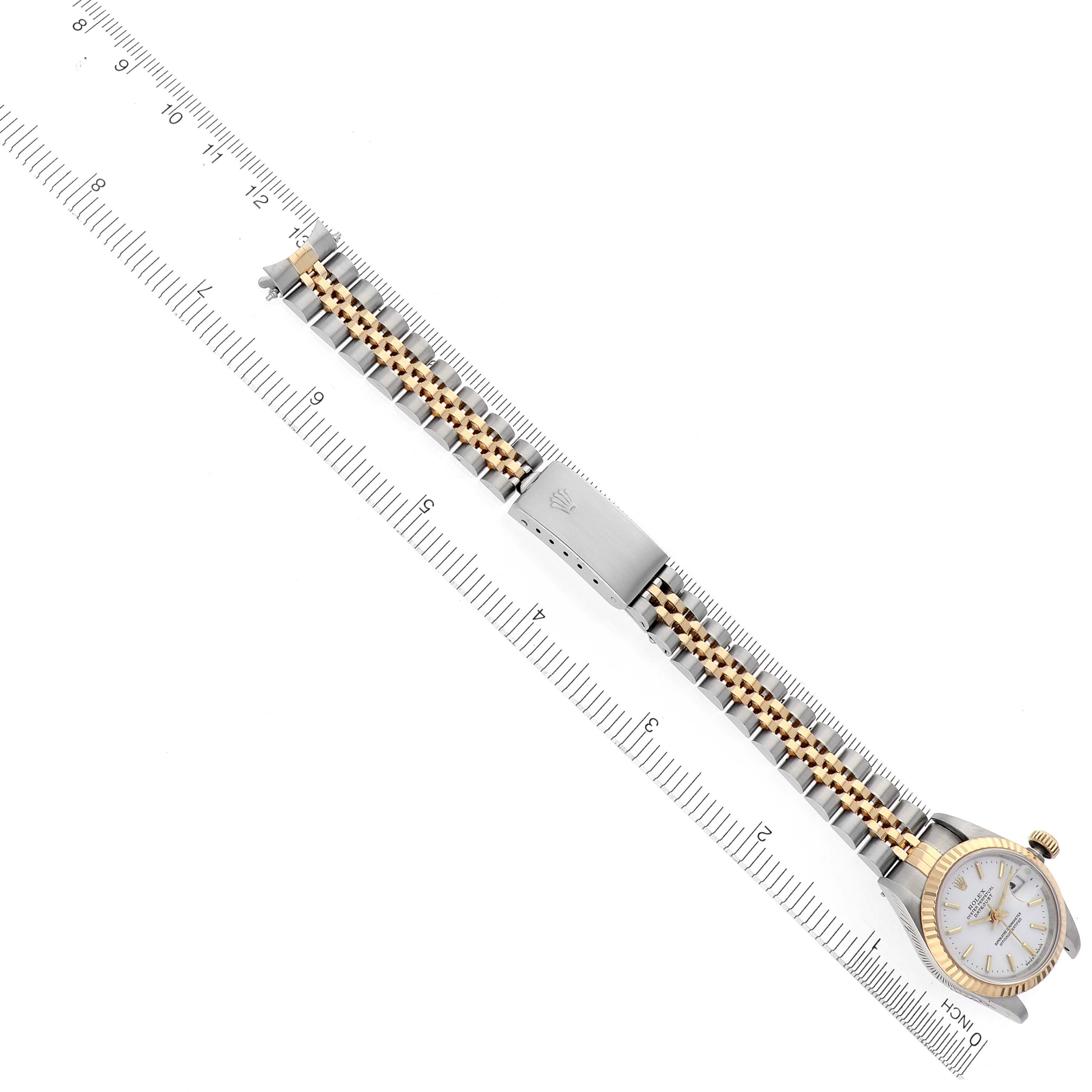 The Rolex Datejust 69173 Women's Steel and Gold (two tone) White Dial 69173 Women's Steel and Gold (two tone) White Dial is shown from a top-down angle, highlighting the watch face, bracelet, and clasp alongside a ruler.