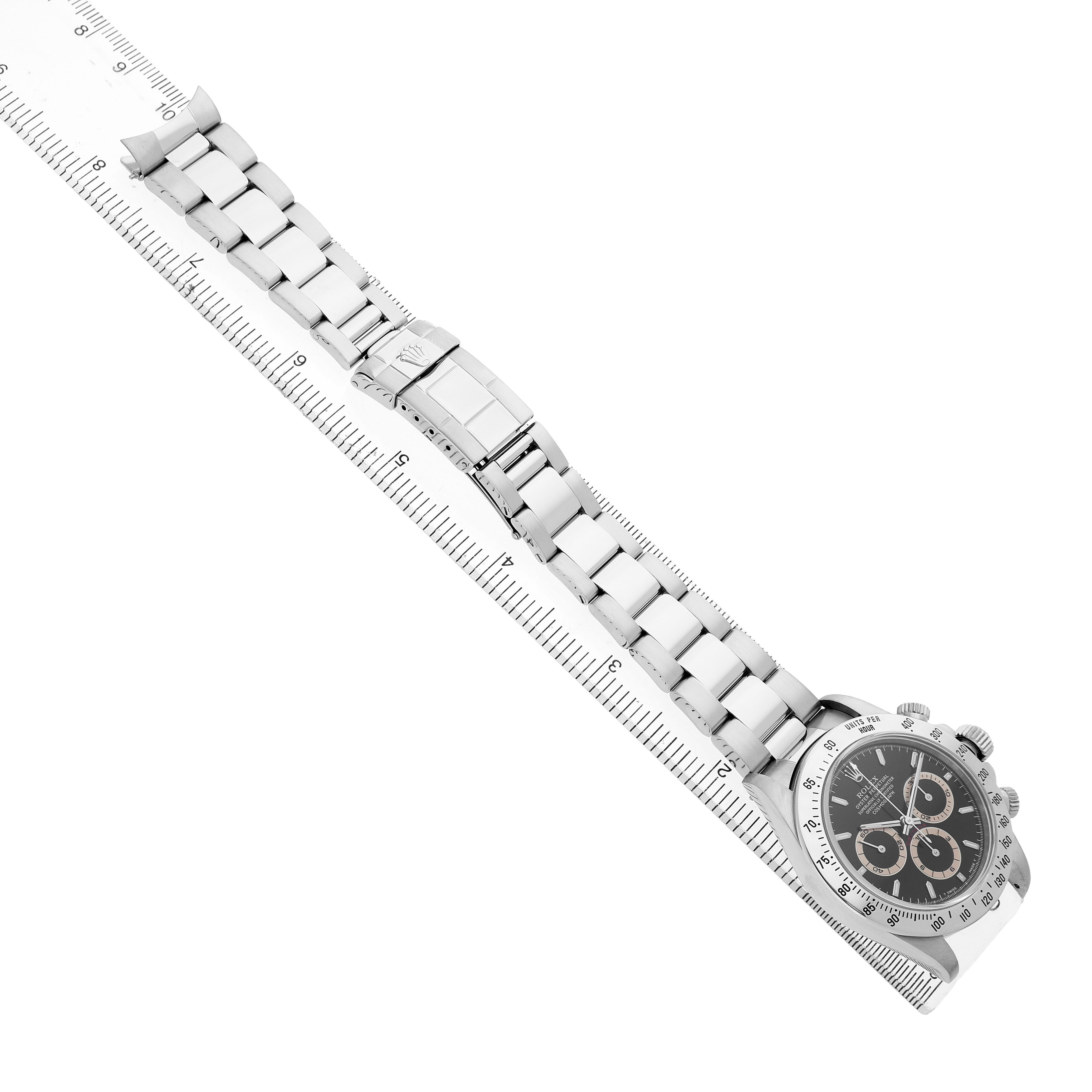 The Rolex Daytona 16520 Men's Stainless Steel Black Dial watch is shown at an angle displaying the face, band, and clasp, laid next to a ruler for size reference.