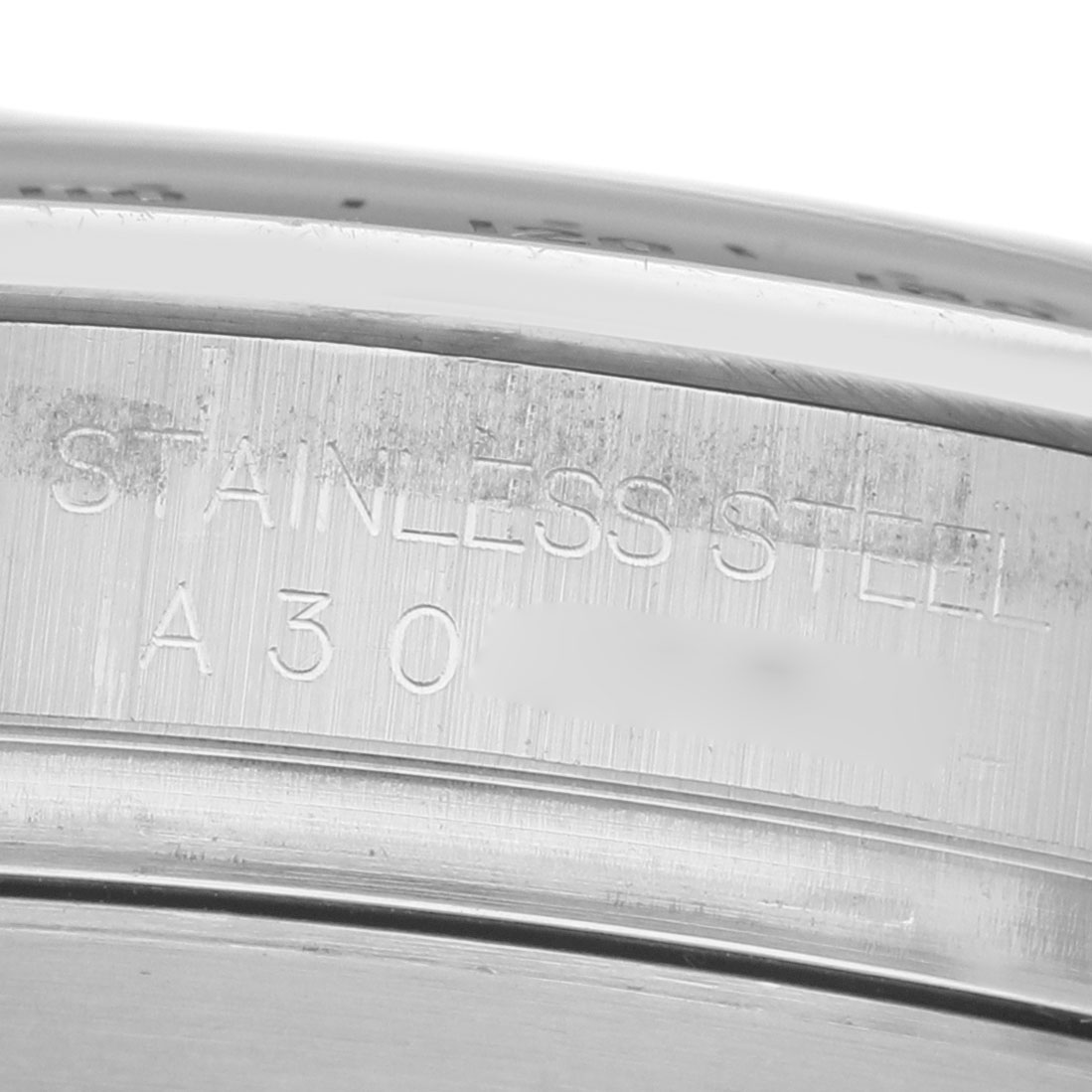 The image displays a close-up of the engraved stainless steel part of a Rolex Daytona 16520 Men's Stainless Steel White Dial watch, focusing on its casing.
