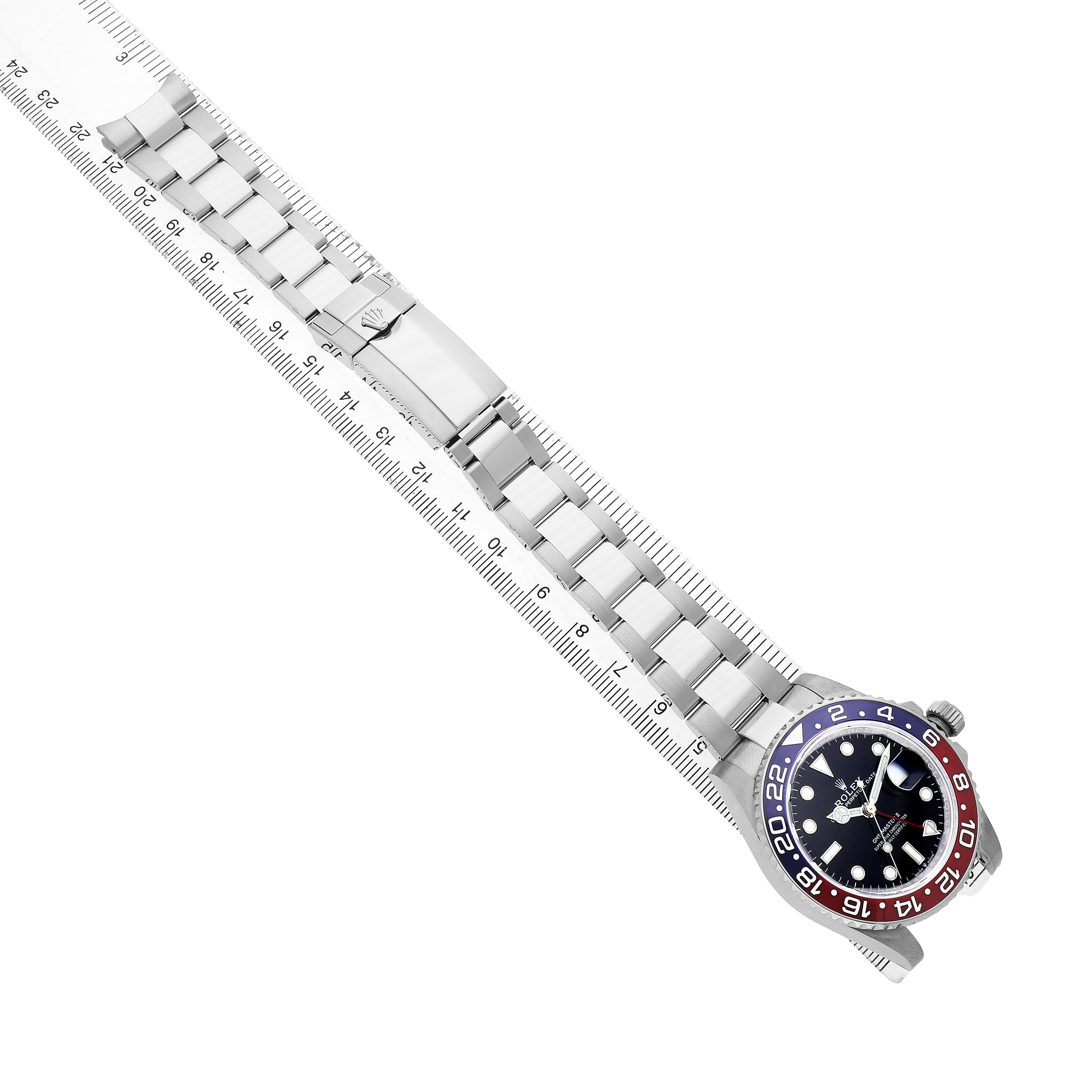 The Rolex GMT-Master 126710BLRO Men's Stainless Steel Black Dial watch is shown from a top-down angle, displaying the face, bezel, and full metal bracelet against a ruler.