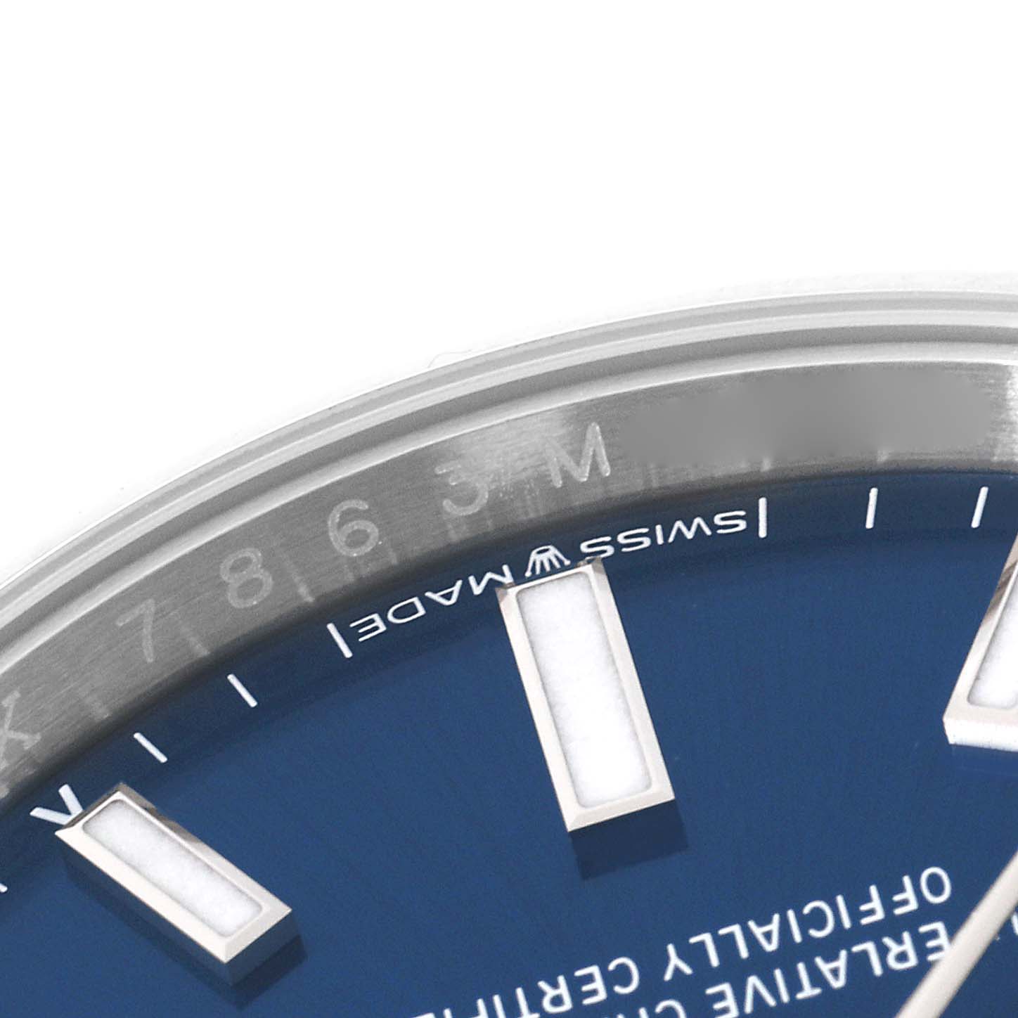 The image shows a close-up angle of the Oyster Perpetual Rolex watch, highlighting the bezel, part of the blue dial, and rectangular hour markers.