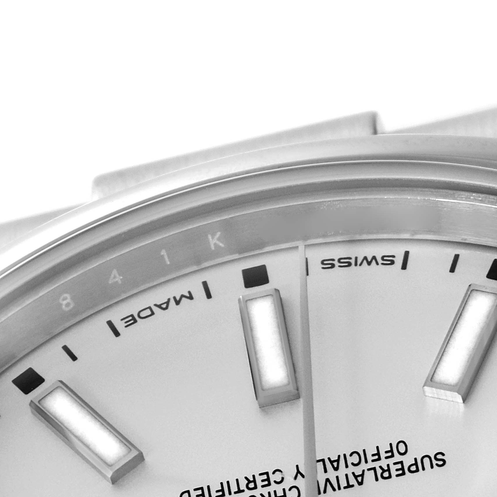 This close-up image of a Rolex Oyster Perpetual 114300 Men's Stainless Steel Silver Dial 114300 Men's Stainless Steel Silver Dial watch shows a portion of the dial, indices, and text including "MADE" and "SWISS."