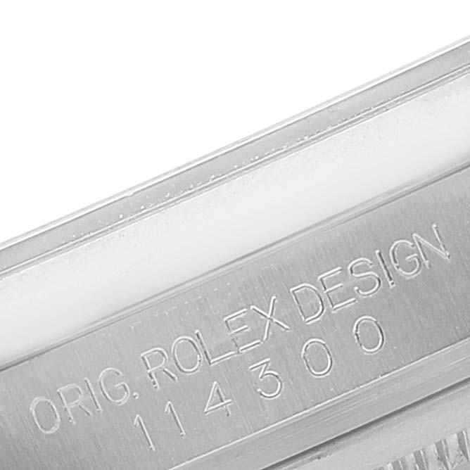 The image shows a close-up of the engraving on the case side of a Rolex Oyster Perpetual 114300 Men's Stainless Steel Silver Dial 114300 Men's Stainless Steel Silver Dial model.