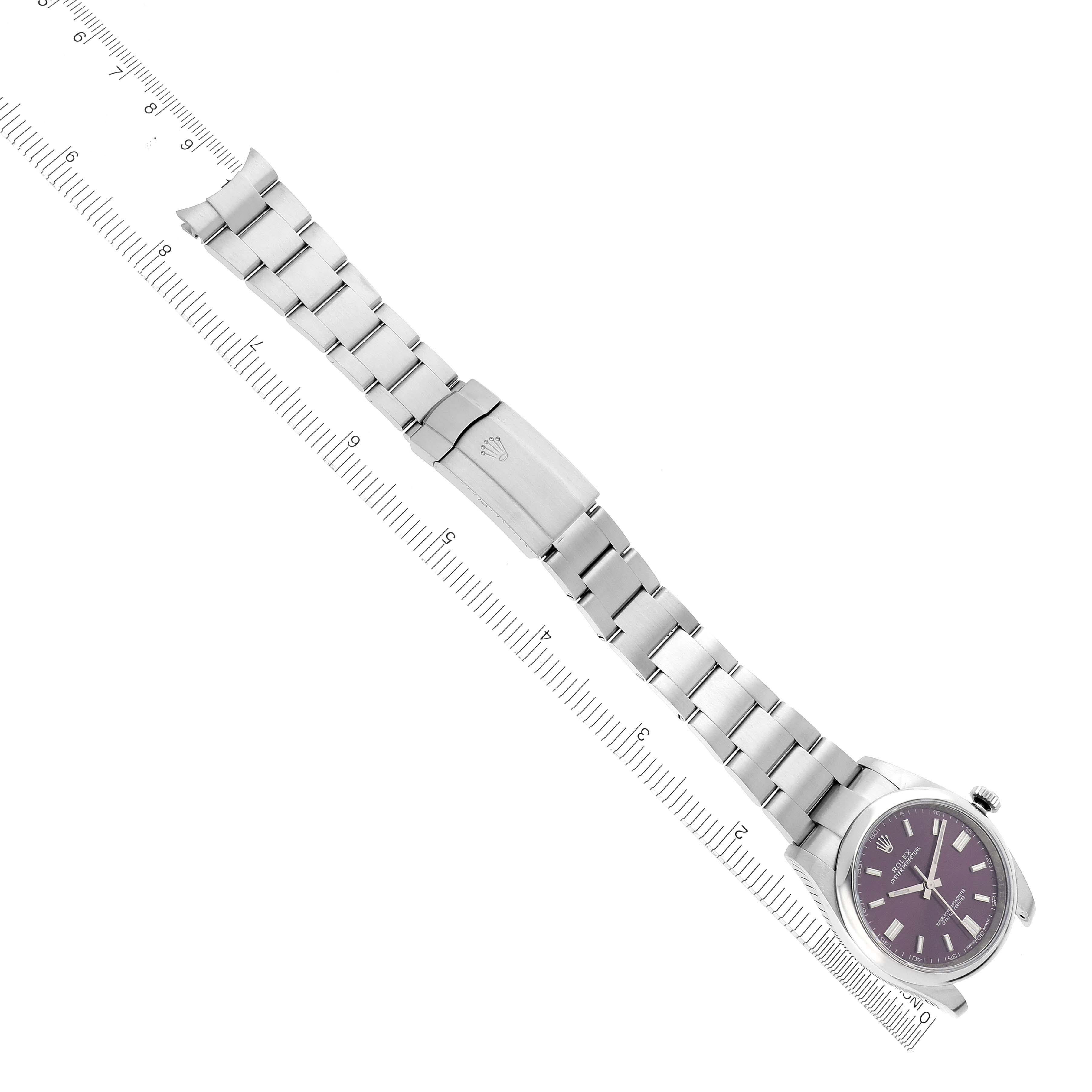The Rolex Oyster Perpetual 116000 Men's Stainless Steel Purple Dial watch is shown from a top view, featuring its bracelet, clasp, and dial alongside a ruler for scale.