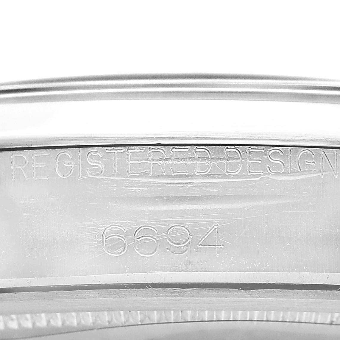 The image shows the side of a Rolex Vintage Collection 6694 Men's Stainless Steel Silver Dial watch case with "Registered Design 6694" engraved.