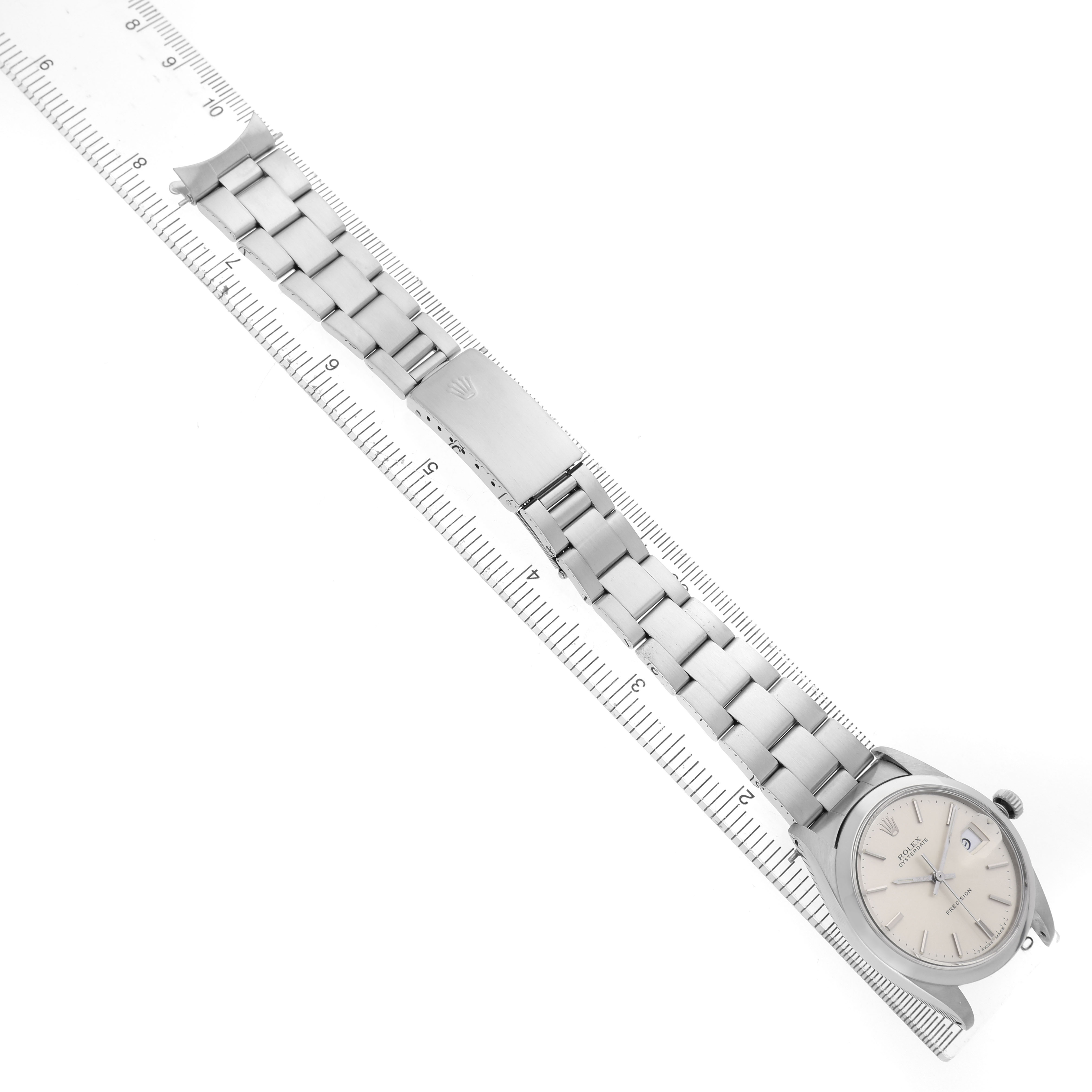 The Rolex Vintage Collection 6694 Men's Stainless Steel Silver Dial watch is shown from a top-down angle, displaying the bracelet, clasp, and face on a ruler.