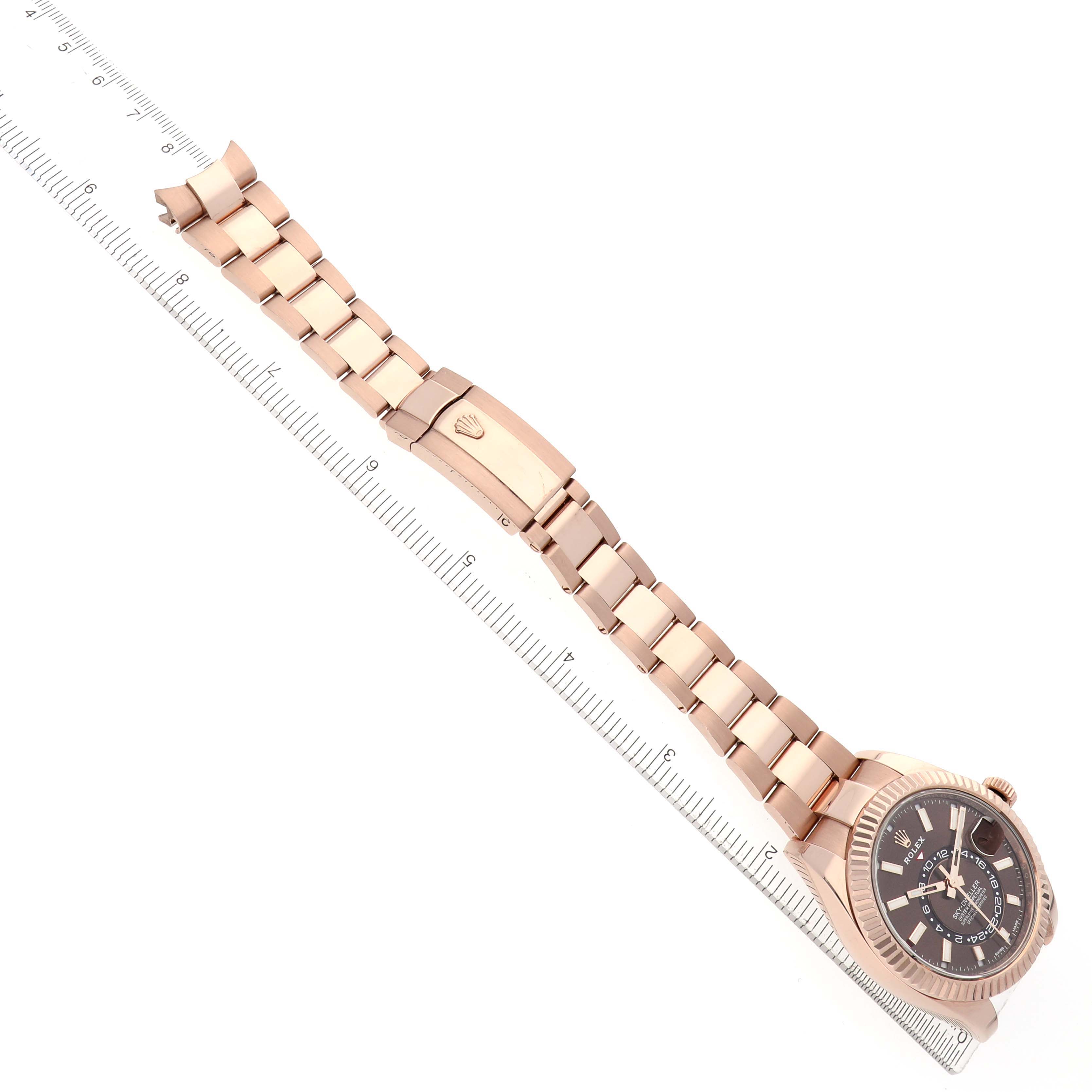 The Rolex Sky-Dweller 326935 Men's Rose Gold Brown Dial watch is shown at a diagonal angle, displaying the bracelet, clasp, and bezel prominently.