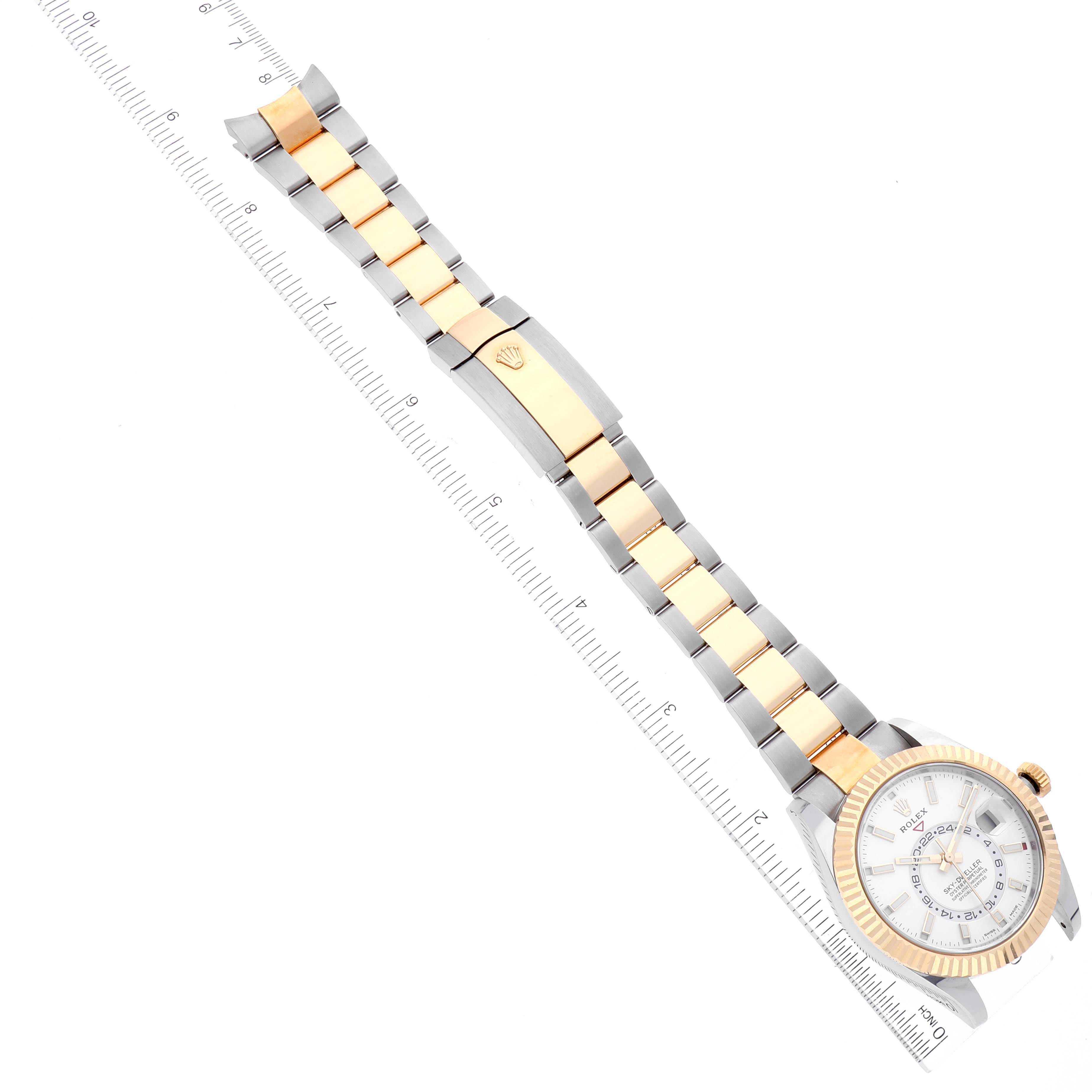 The Rolex Sky-Dweller 326933 Men's Steel and Gold (two tone) White Dial 326933 Men's Steel and Gold (two tone) White Dial watch shown is angled diagonally with a close-up of its face, bracelet, and clasp, alongside a ruler for scale.