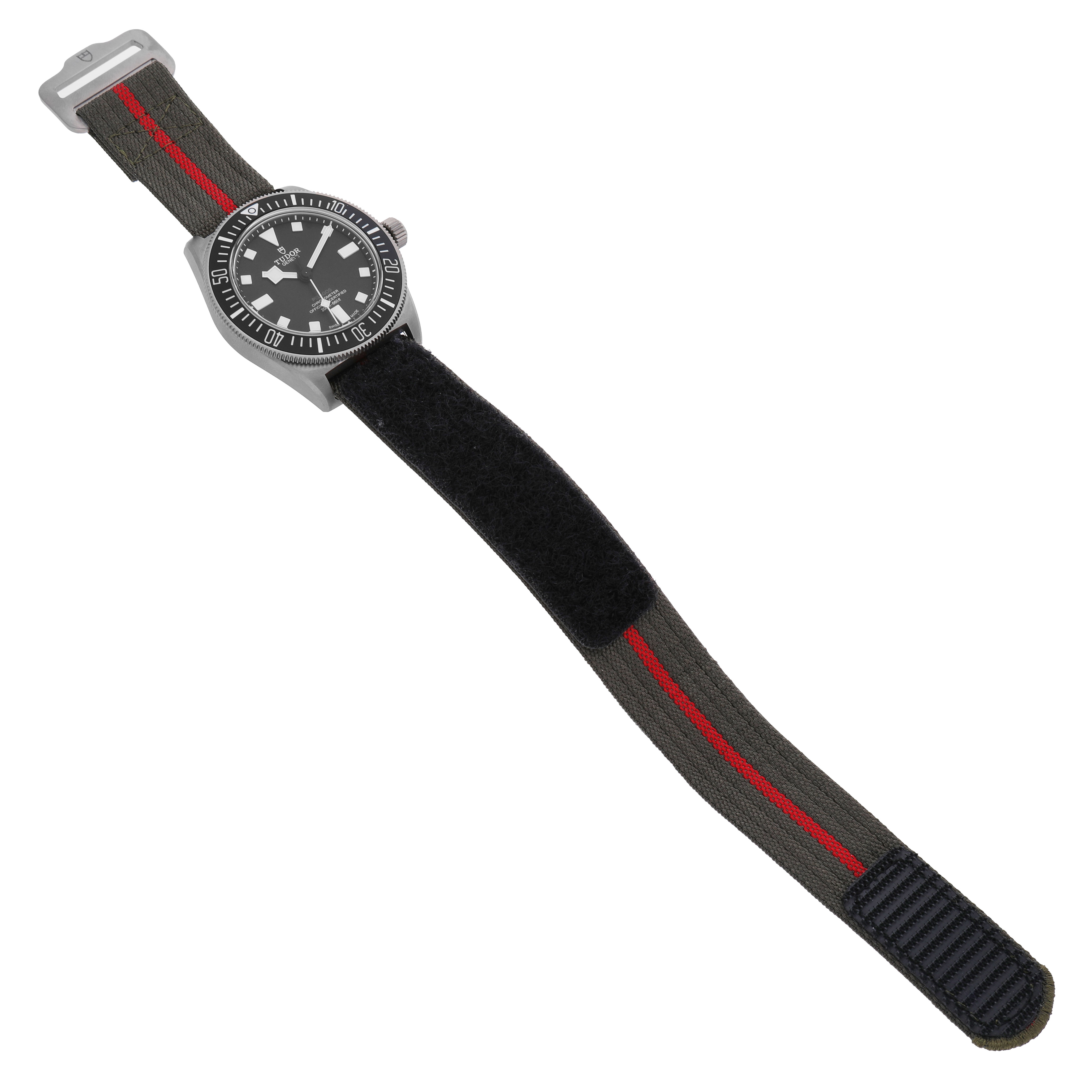 The Tudor Pelagos 25717 Men's Titanium Black Dial watch is shown from a top-down angle, displaying the dial and full fabric strap.
