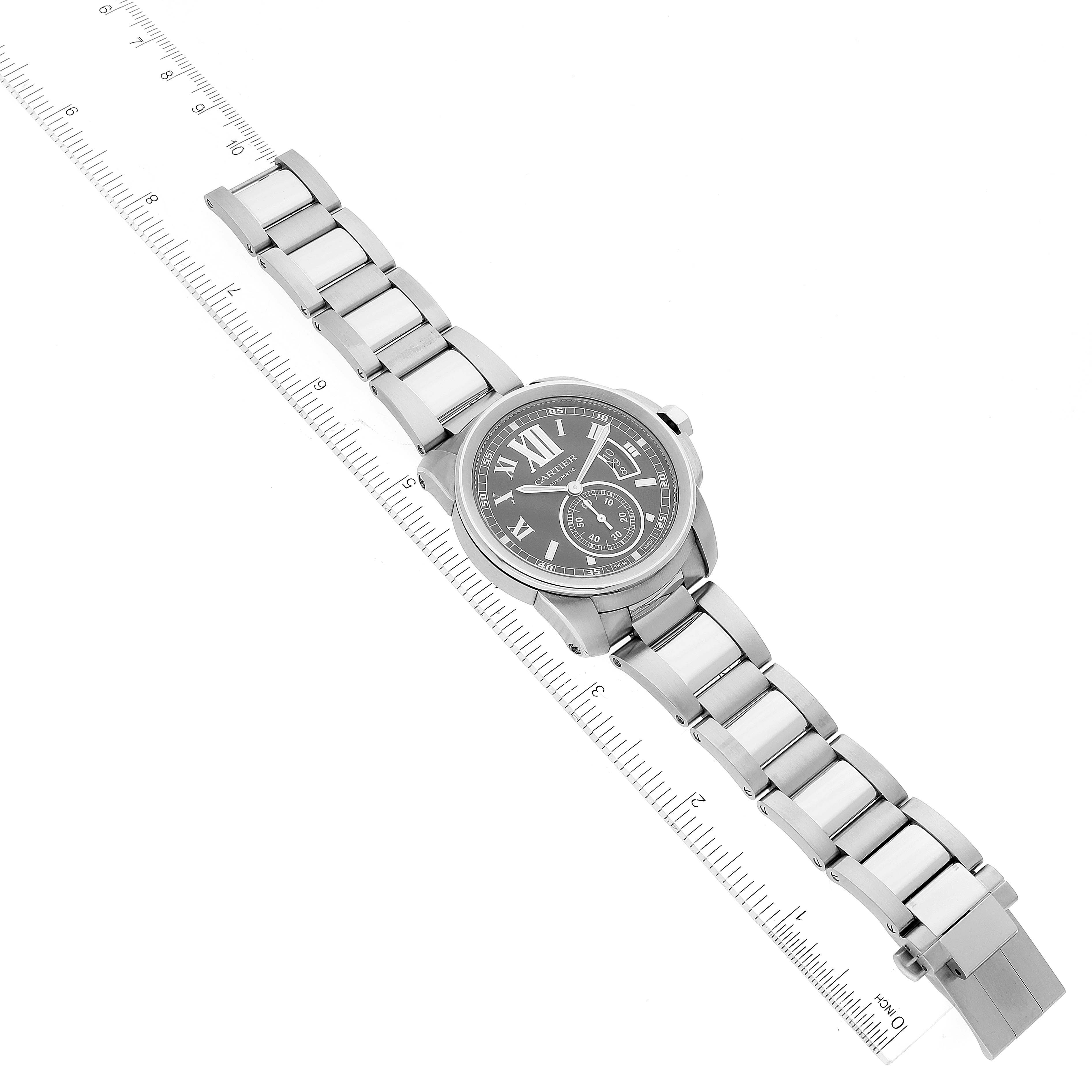 The image shows a top-down view of a Calibre de Cartier watch by Cartier, laid on a ruler for size reference.