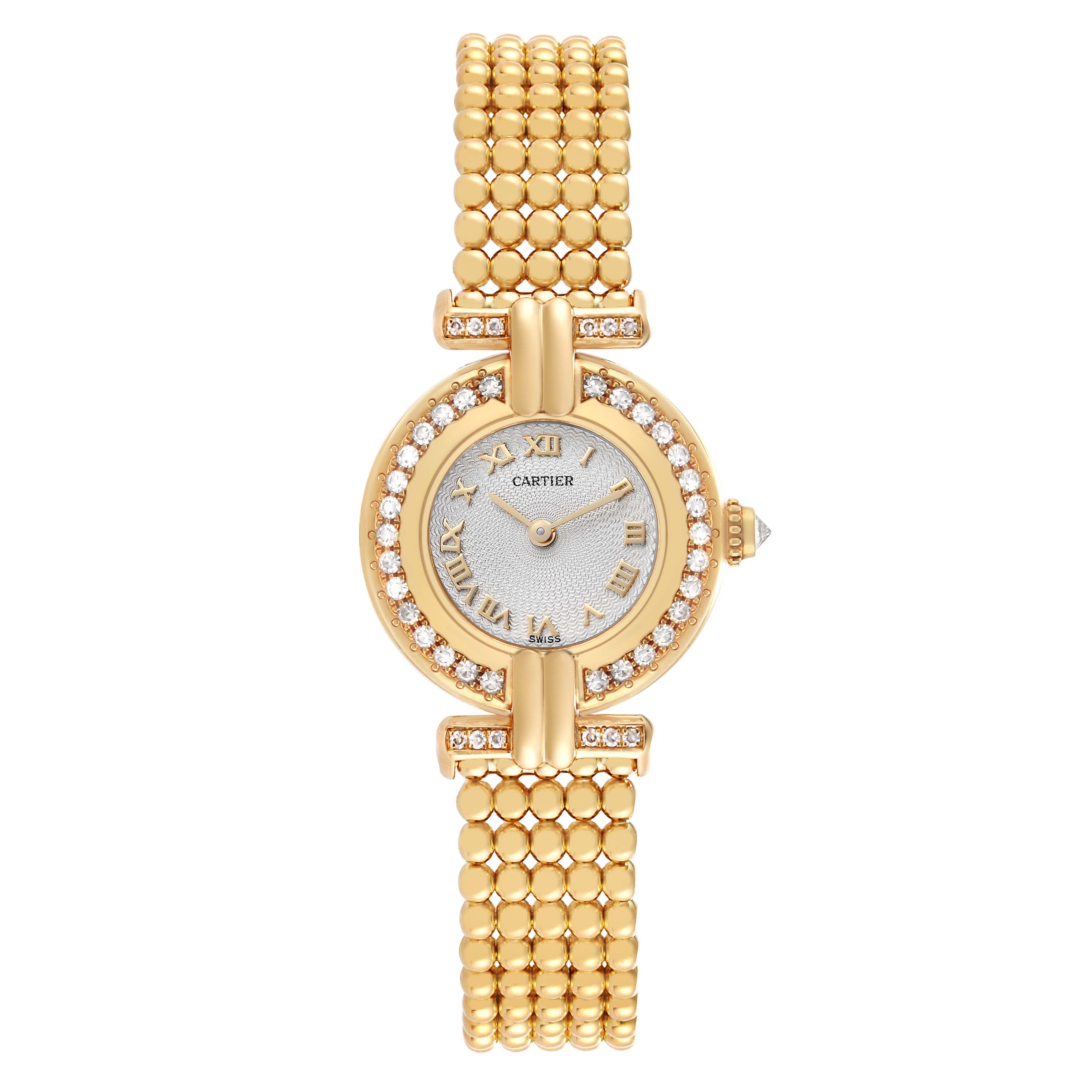 The Cartier Colisee WB1018A8 Women
s Yellow Gold Silver Dial watch is shown from a top view, displaying its round face, Roman numerals, diamond bezel, and gold bracelet.