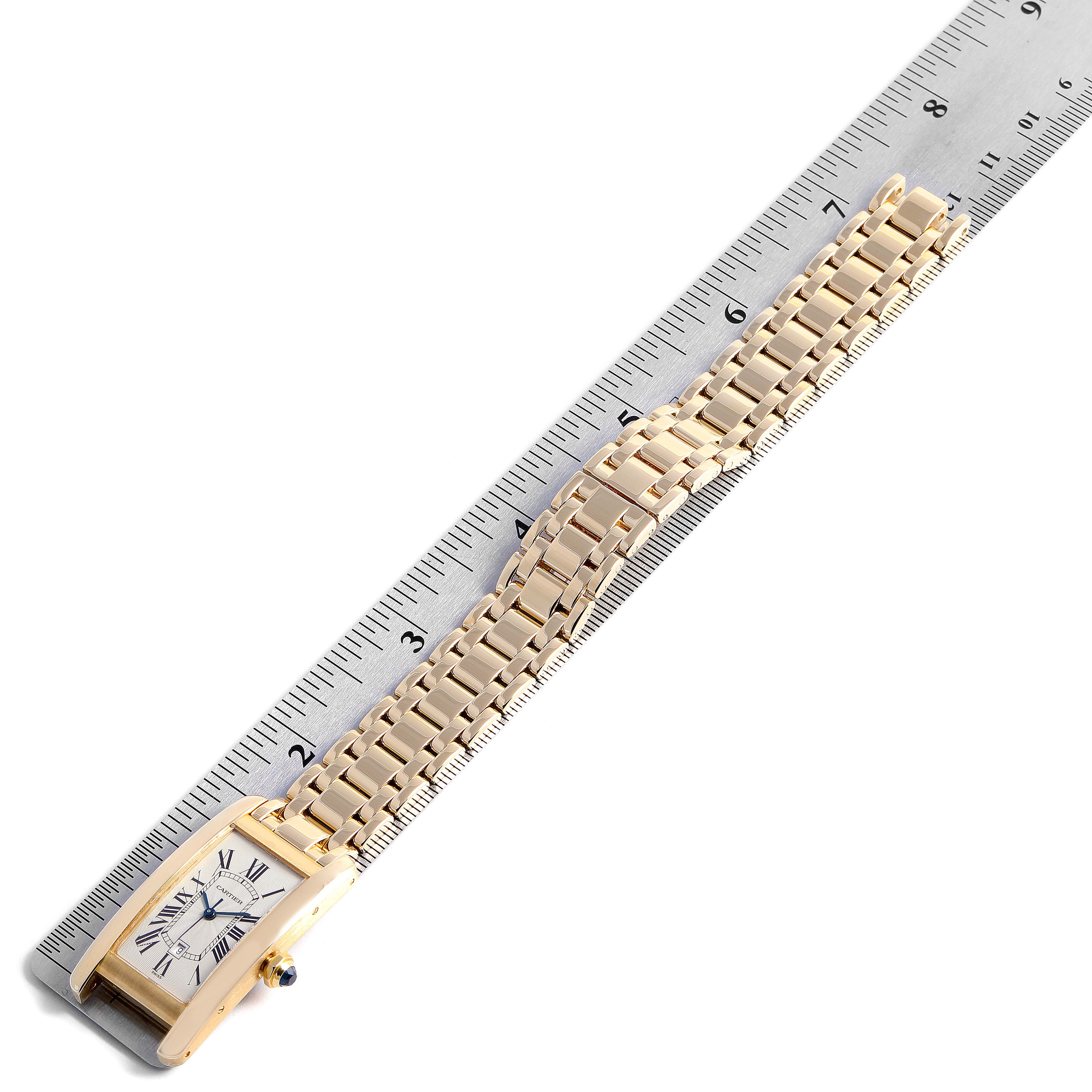 This image shows an angled top view of the Cartier Tank Américaine watch with the dial, casing, and bracelet against a ruler for size reference.