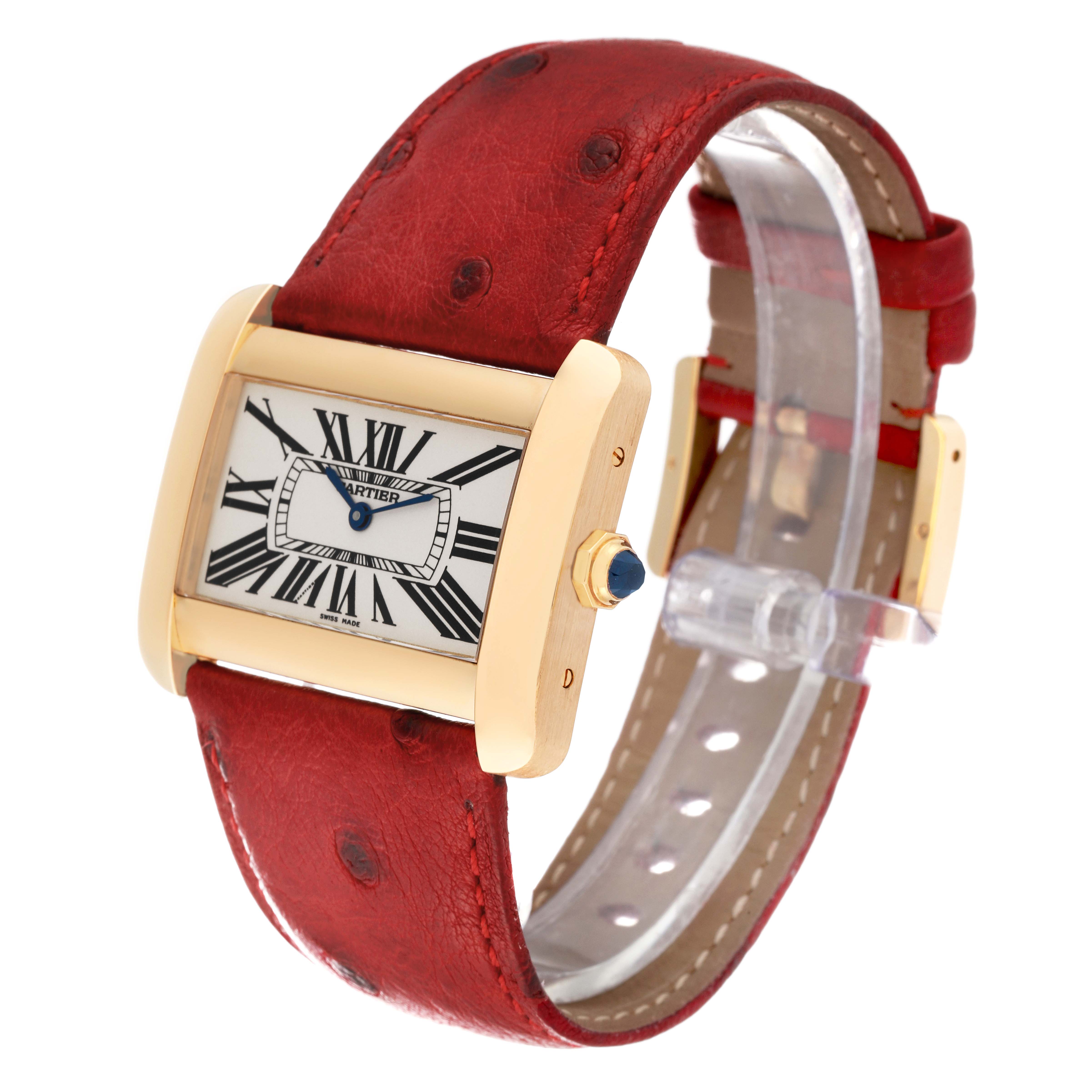The Tank Divan model by Cartier is shown from a front angle, displaying its rectangular face, gold case, red leather strap, and crown.