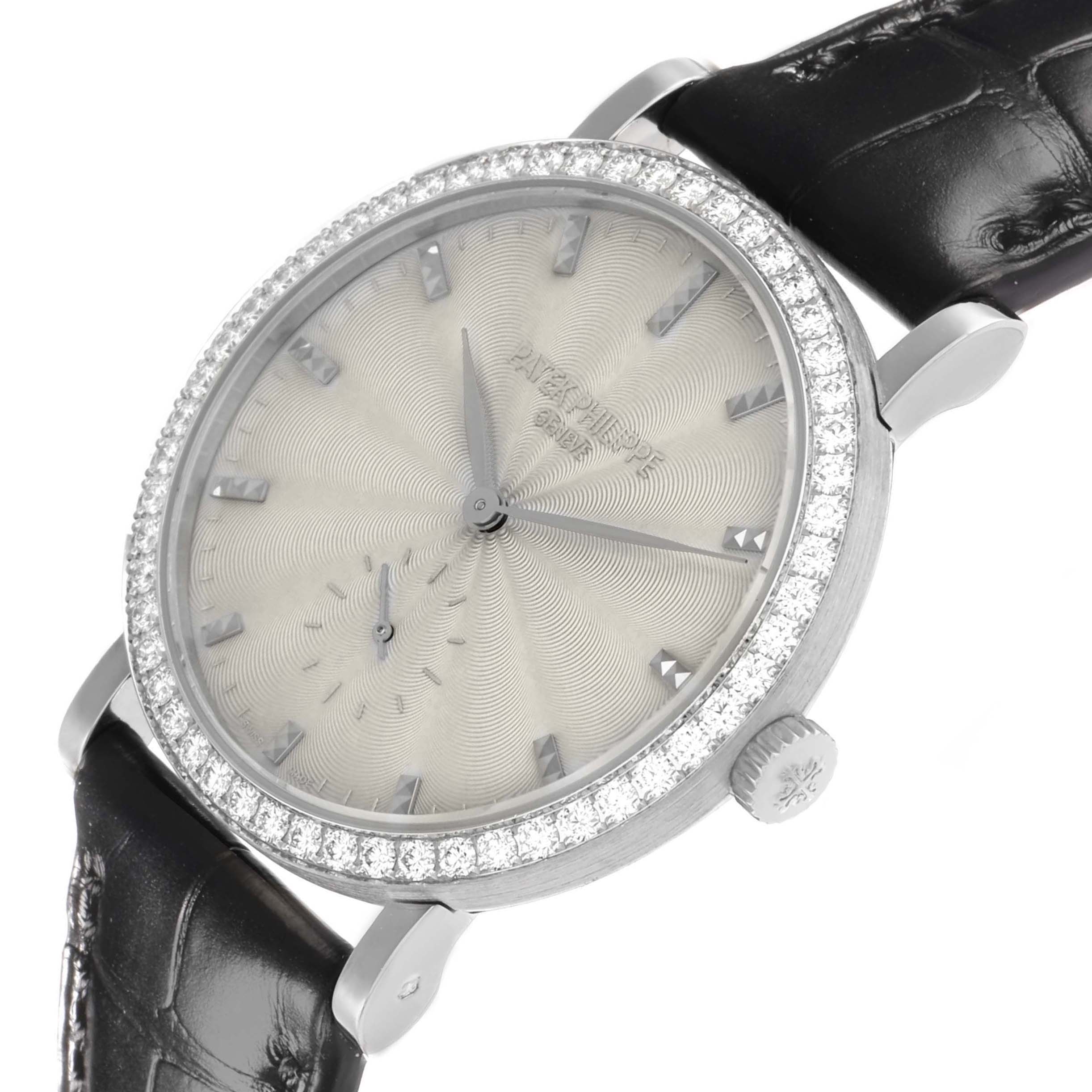 The Calatrava by Patek Philippe is shown at a tilted angle, highlighting its textured dial, diamond bezel, crown, and leather strap.