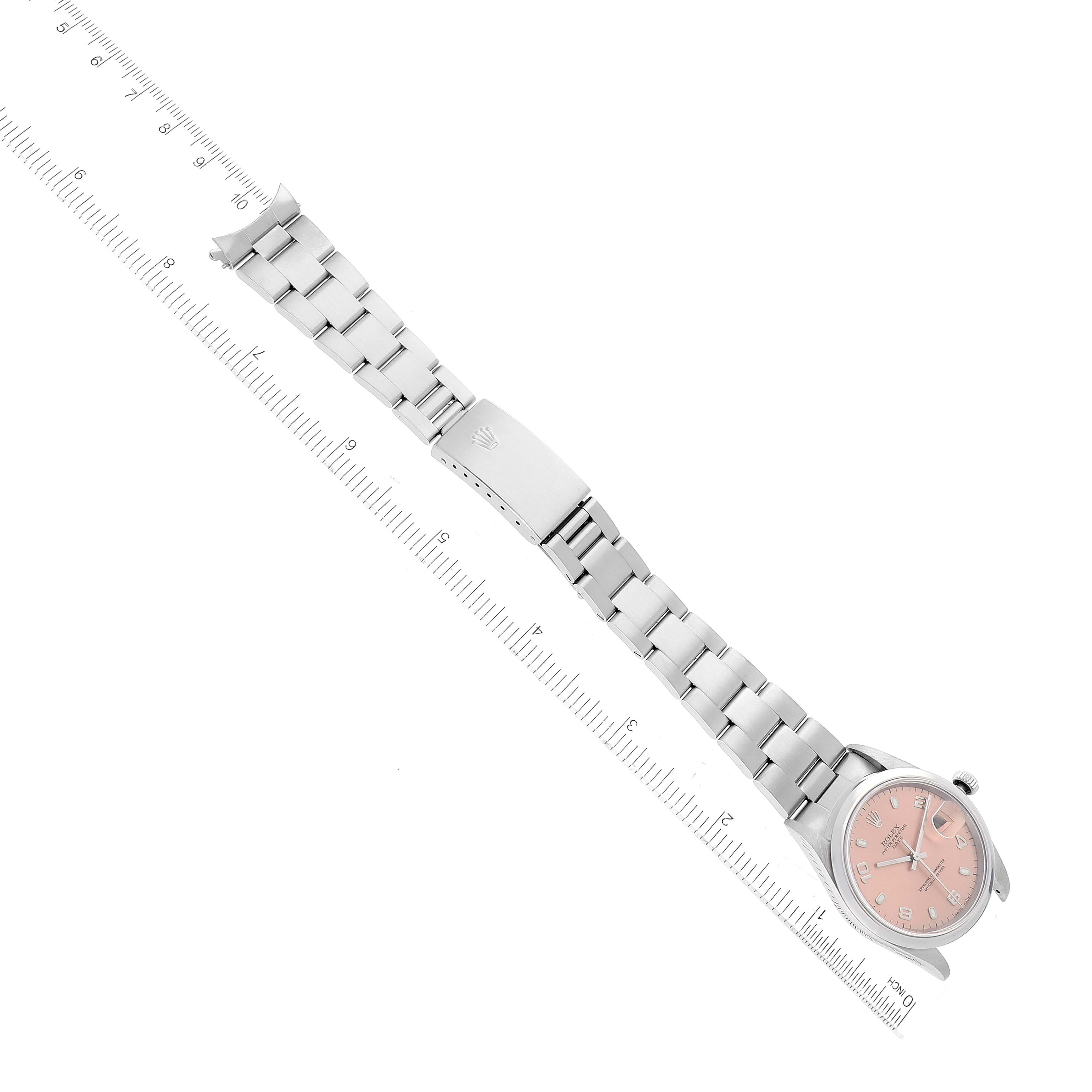 The image shows a Rolex Date 15200 Men's Stainless Steel Pink Dial 15200 Men's Stainless Steel Pink Dial model watch positioned diagonally with its full bracelet and clasp, aligned next to a ruler.