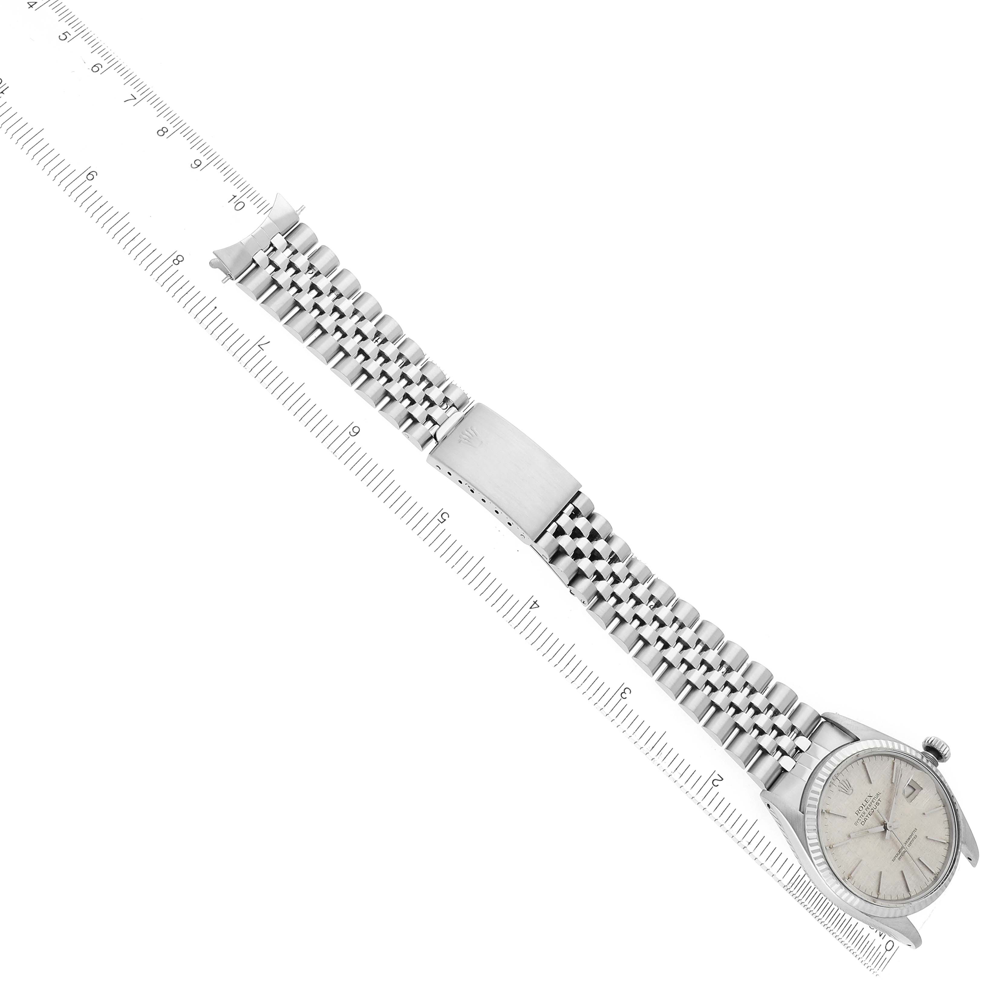 The image shows a Rolex Datejust 16014 Men
s Stainless Steel Silver Dial watch at a diagonal angle, focusing on the full bracelet and watch face alongside a ruler.