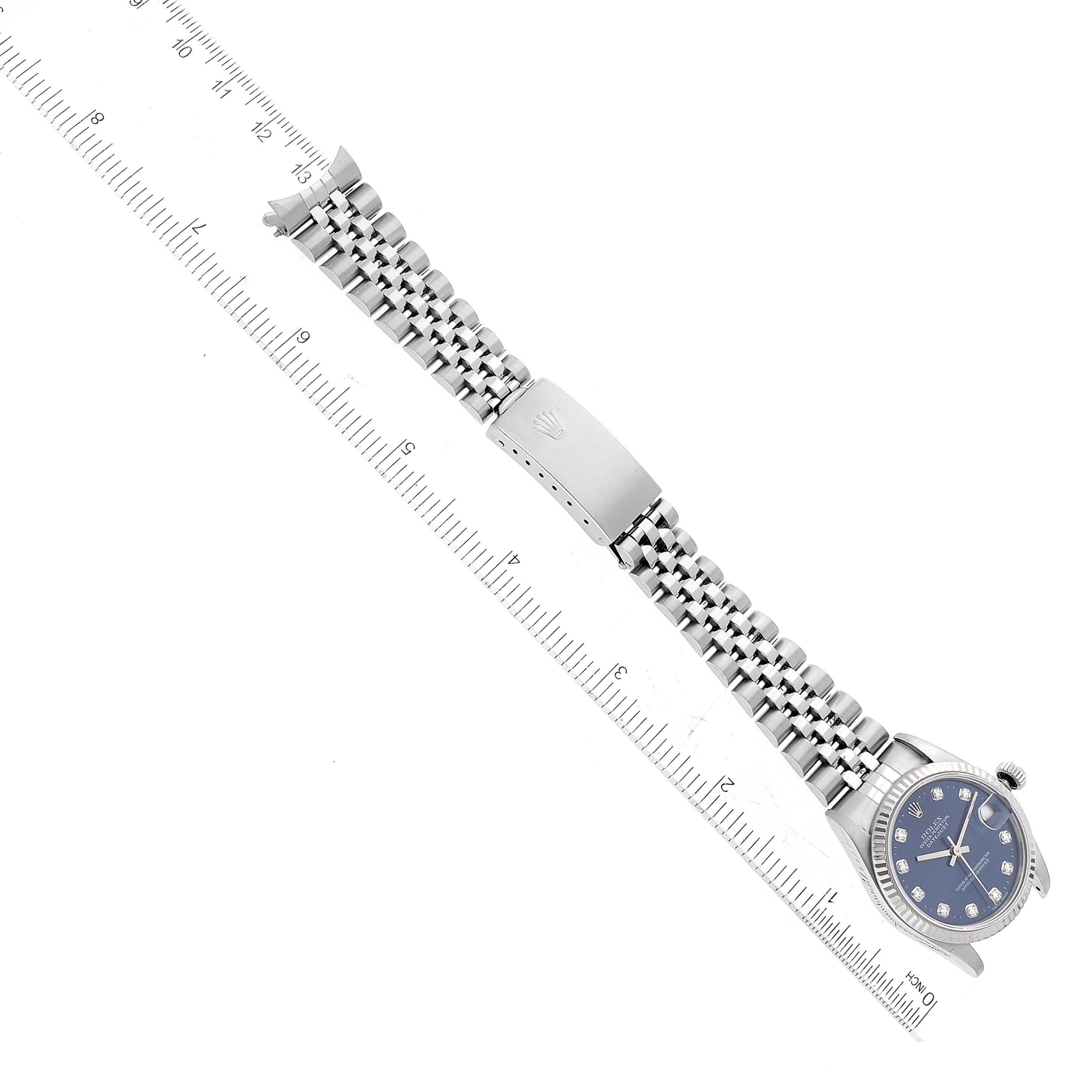 The image shows a Mid-Size Rolex watch laid flat, with its face, bracelet, and clasp visible, alongside a ruler for size reference.
