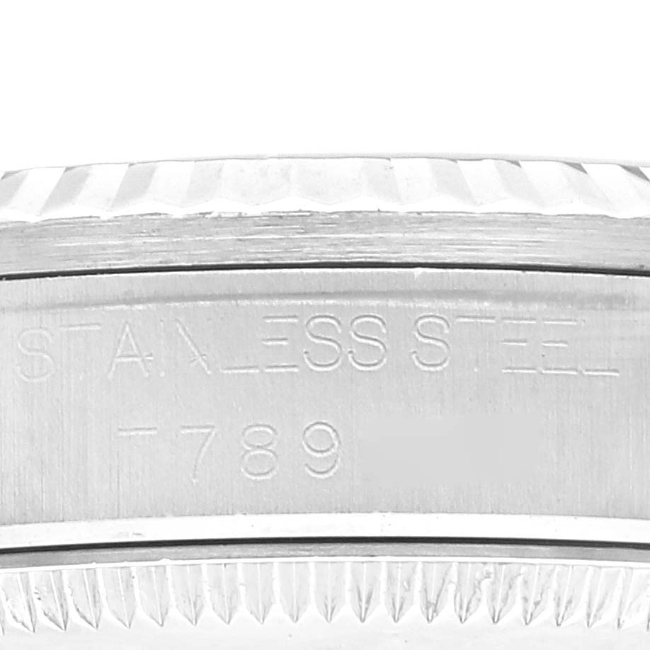 The image shows a close-up of the stainless steel case and fluted bezel of a Mid-Size Rolex watch.