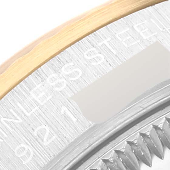 Close-up of a Mid-Size Rolex watch showing the engraved bezel, including stainless steel text and partial serrated edge.
